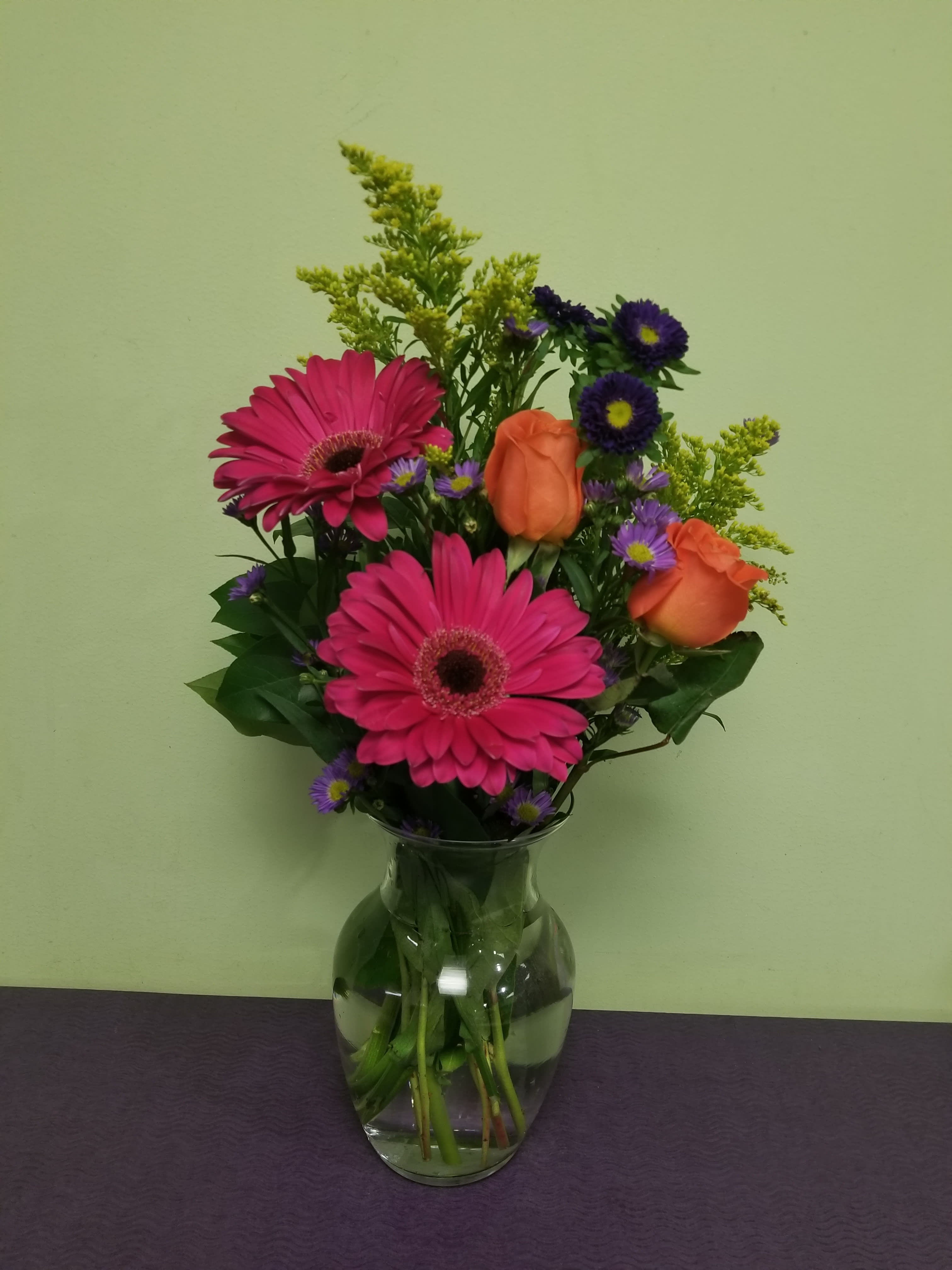 Pink gerbera daisies and orange roses in a glass vase