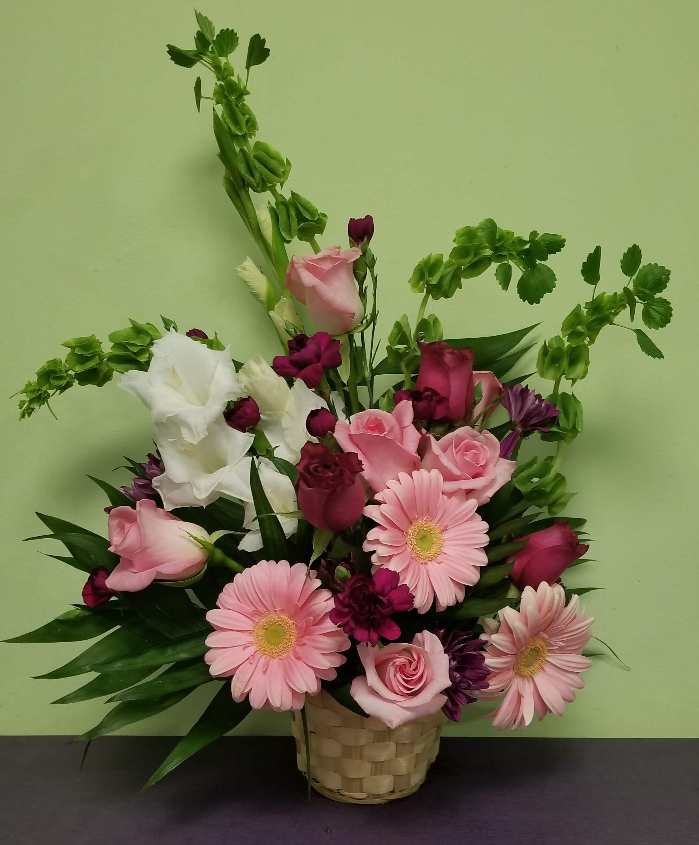Pink and white mixed flower arrangement in a woven basket
