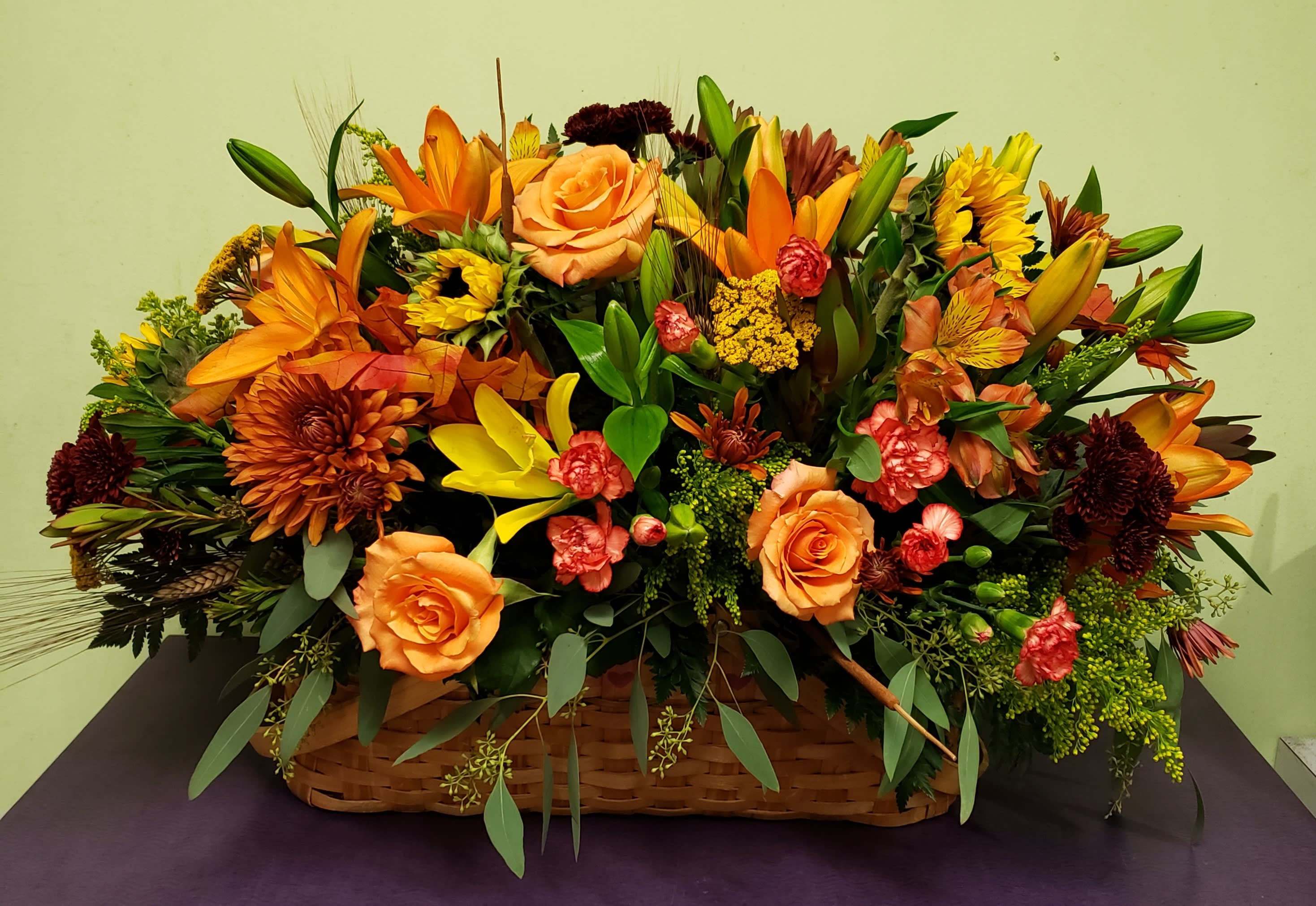 Basket arrangement of orange and yellow flowers with roses and lilies