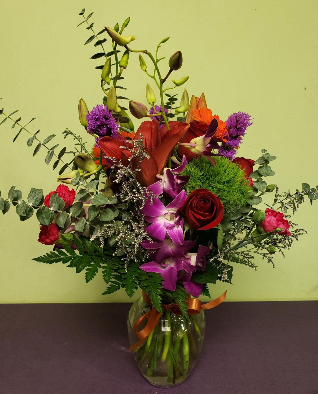 Mixed bouquet in a glass vase with red, purple, and orange flowers