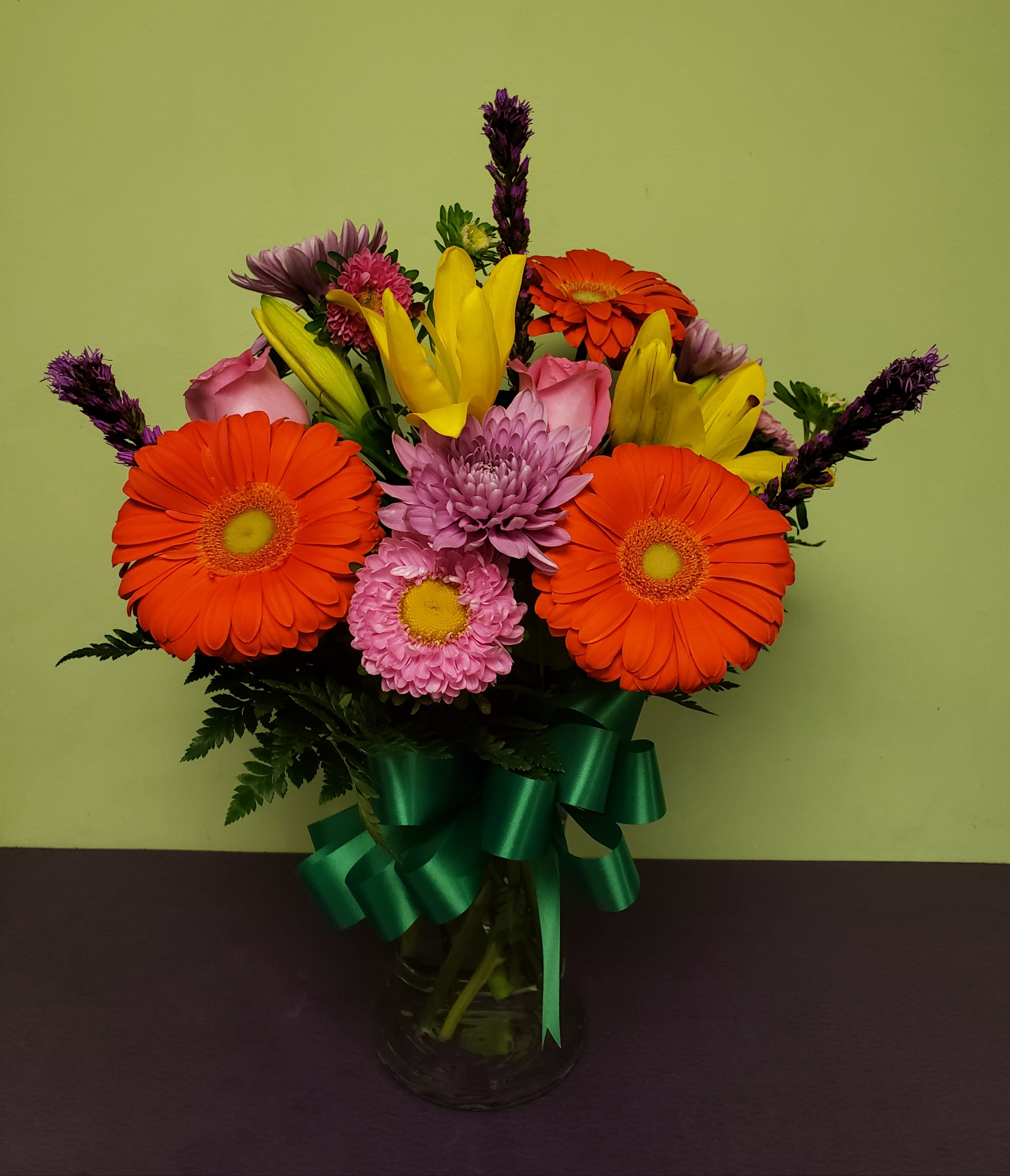 Bright mixed bouquet with gerbera daisies, lilies, and chrysanthemums in a glass vase