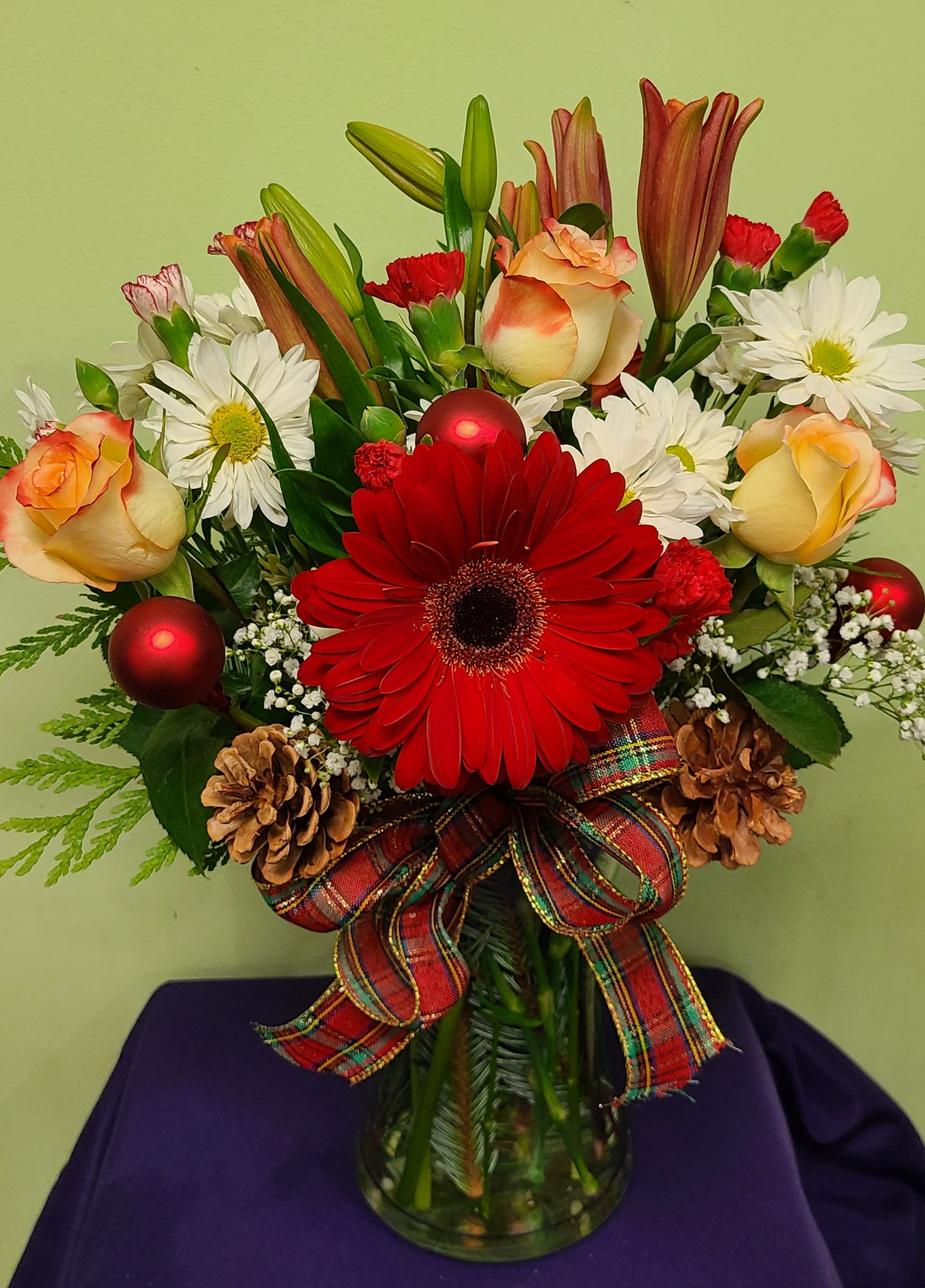 Red gerbera bouquet with white daisies, peach roses, and ribbon in a glass vase