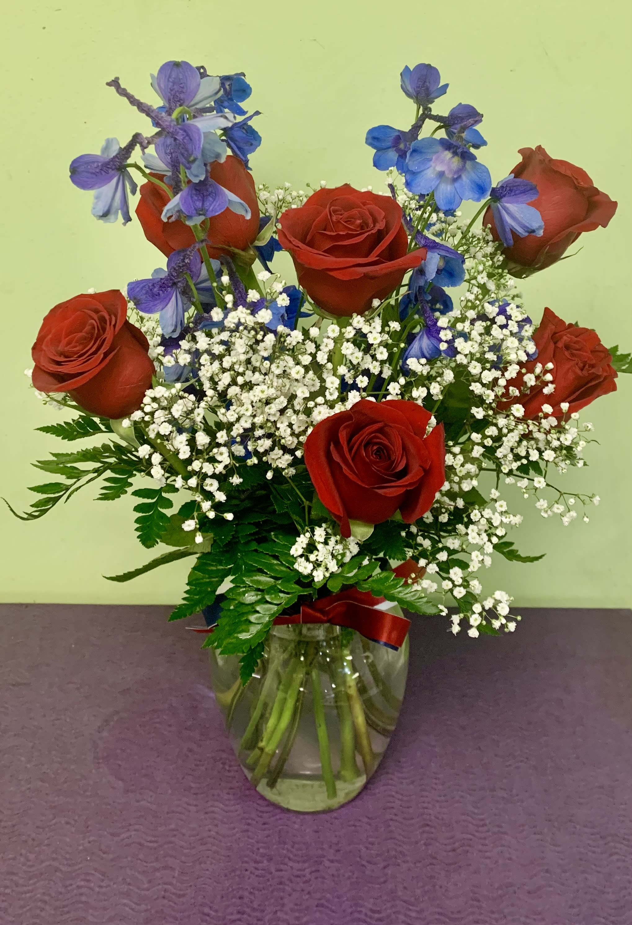 Red roses and blue-purple flowers in a glass vase