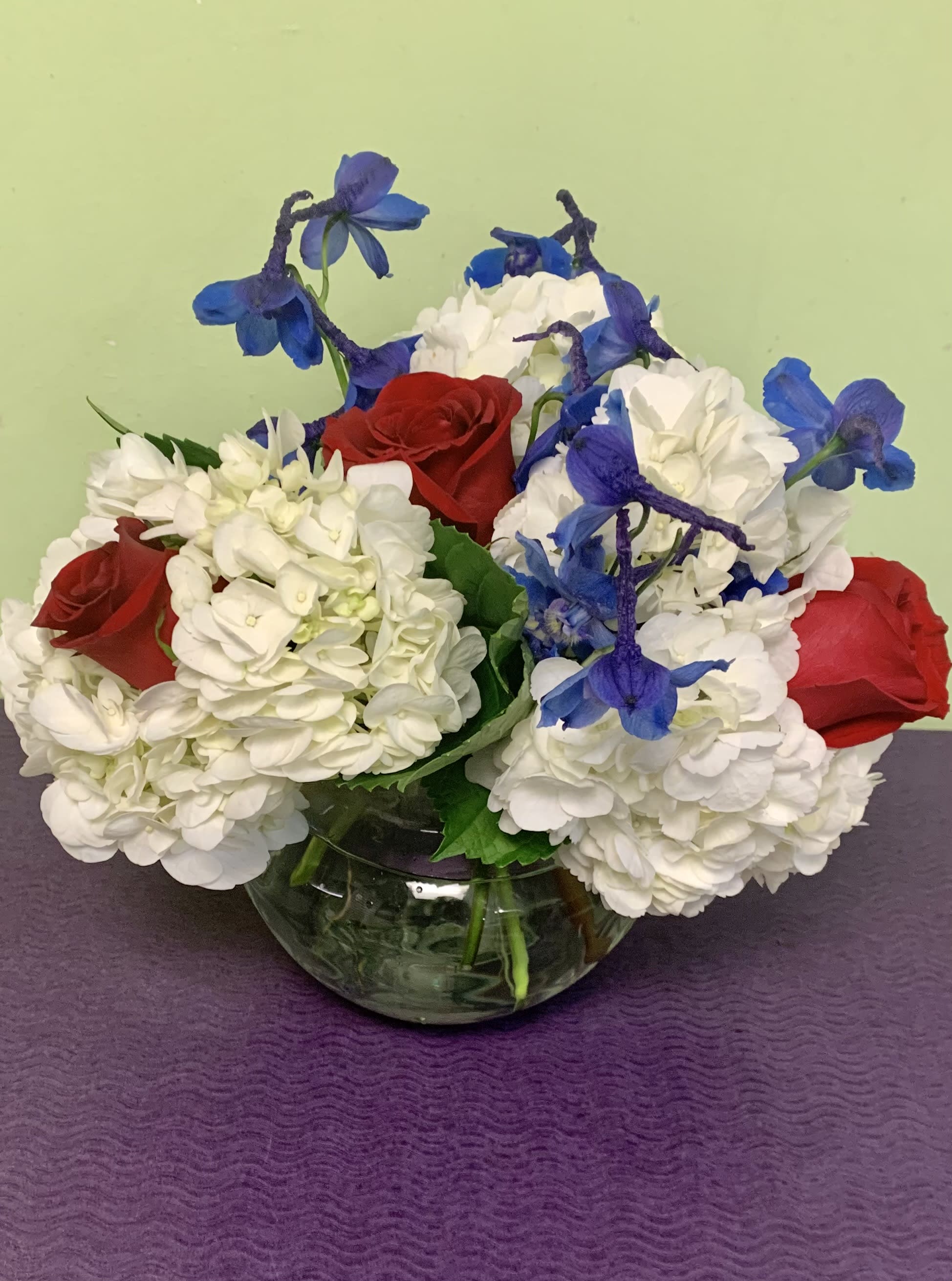 Red roses and white hydrangeas with blue flowers in a glass vase