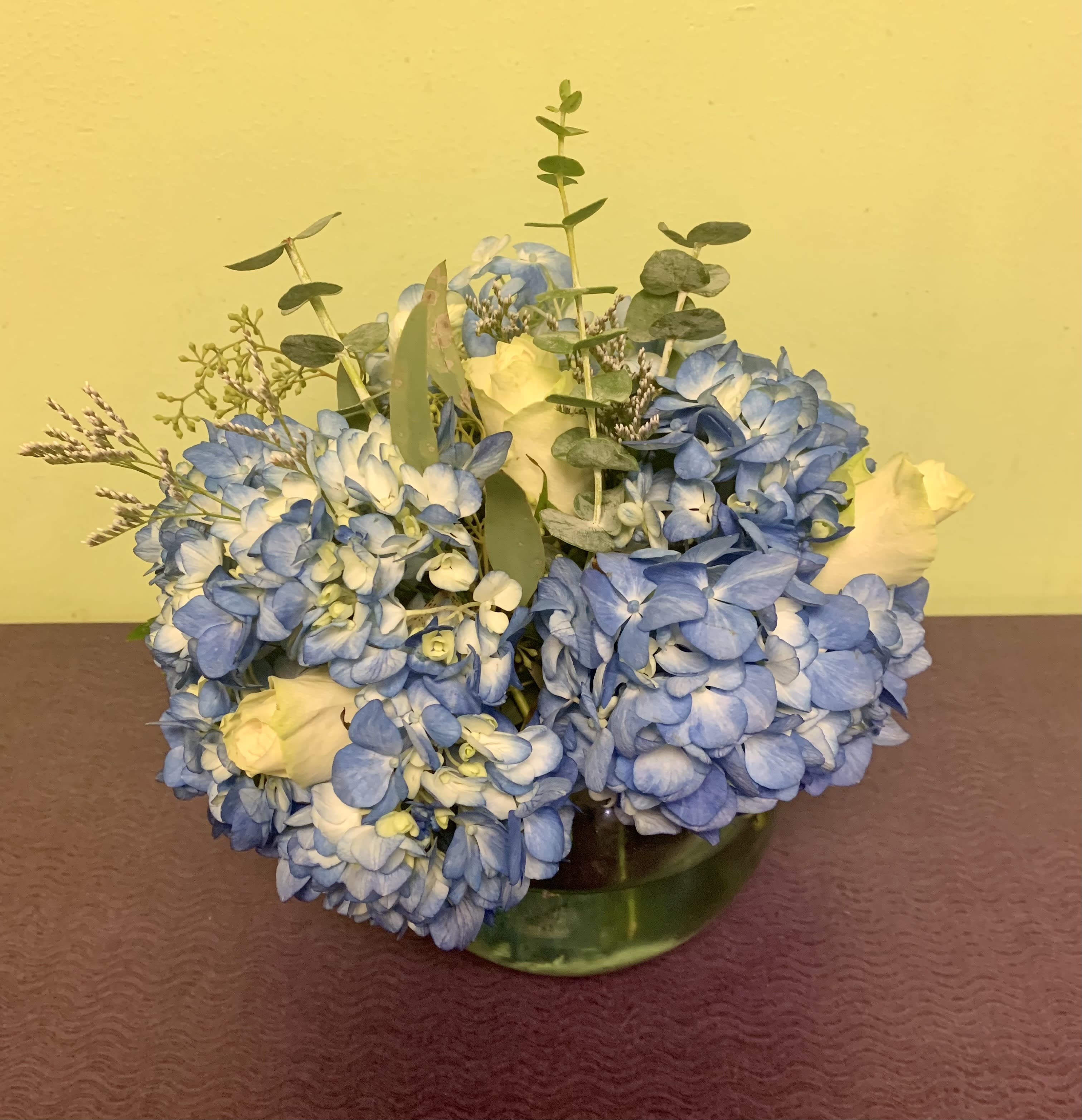 Blue hydrangea bouquet with white roses in a glass vase