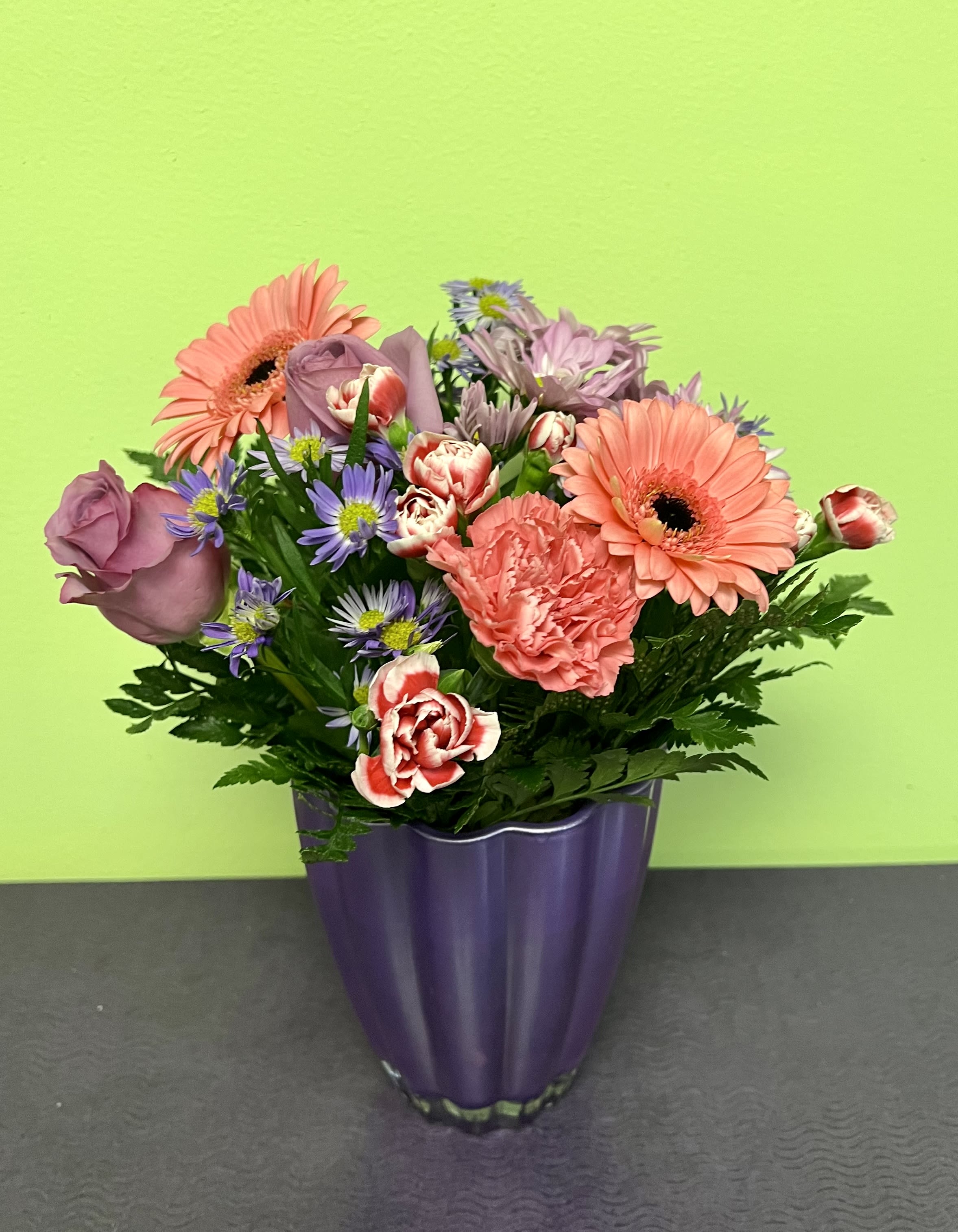 Mixed bouquet of pink and purple flowers in a purple vase
