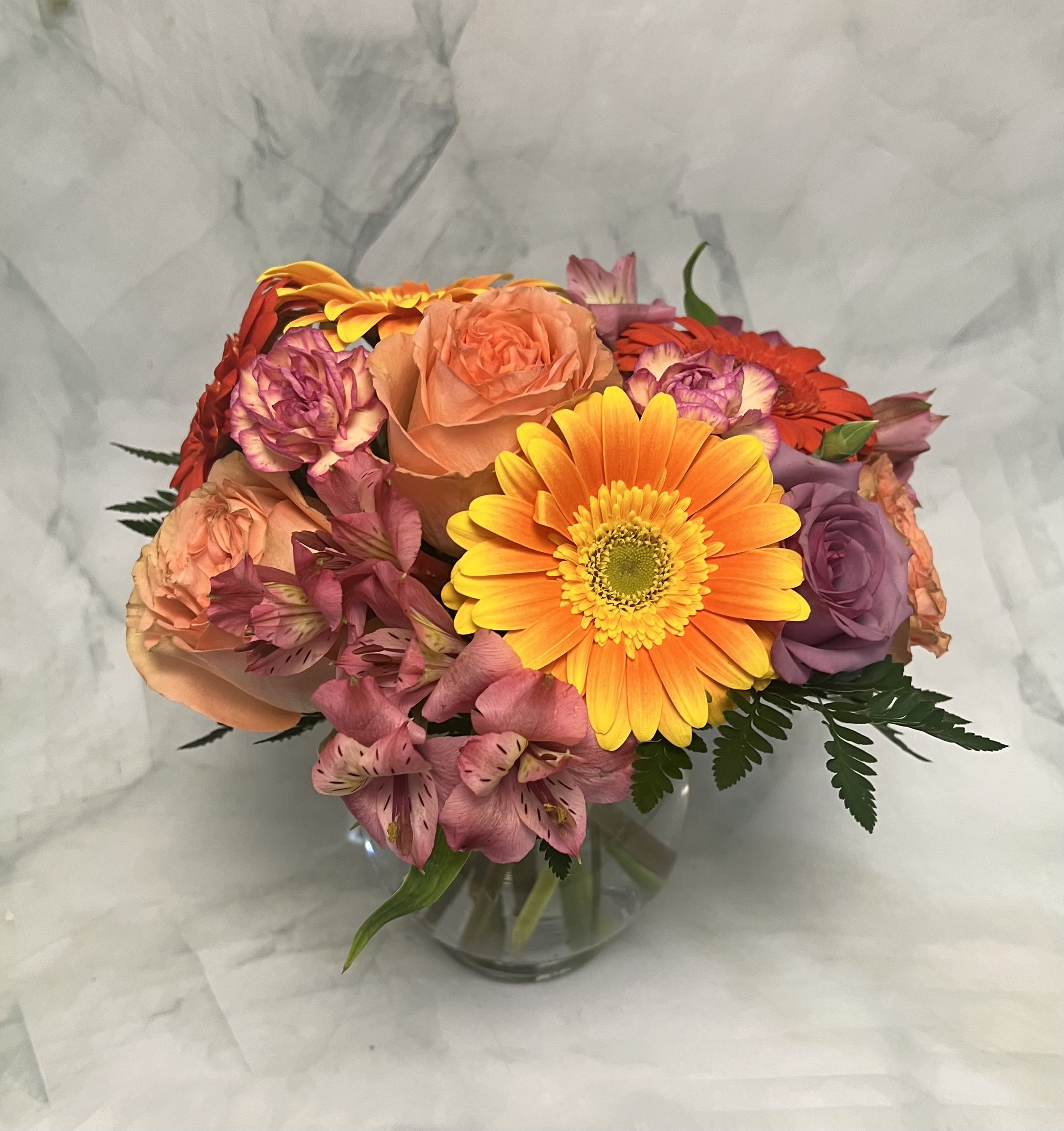 Mixed bouquet of roses, gerbera daisies, and alstroemeria in a glass vase