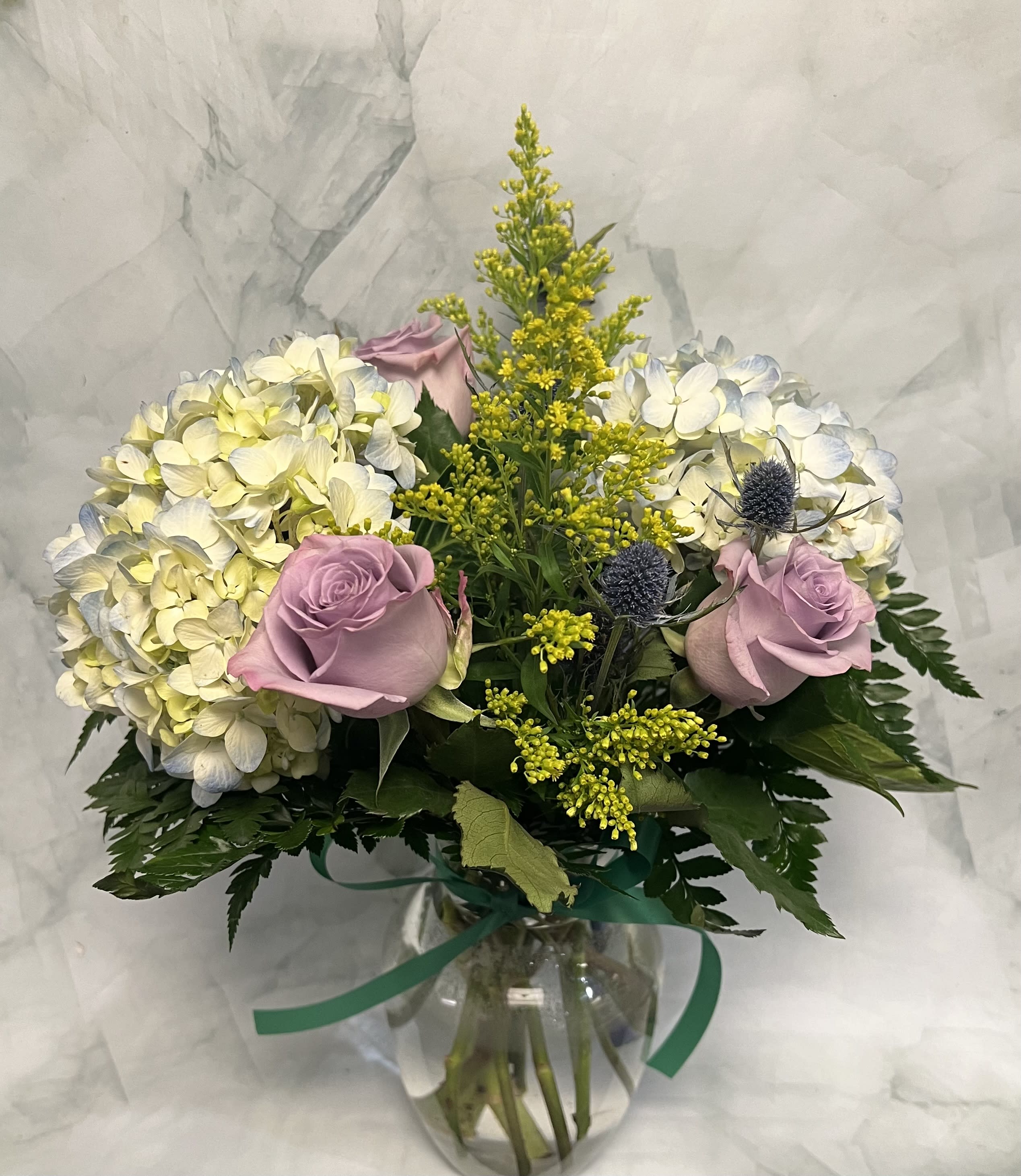 Bouquet of pale hydrangeas and lavender roses in a glass vase
