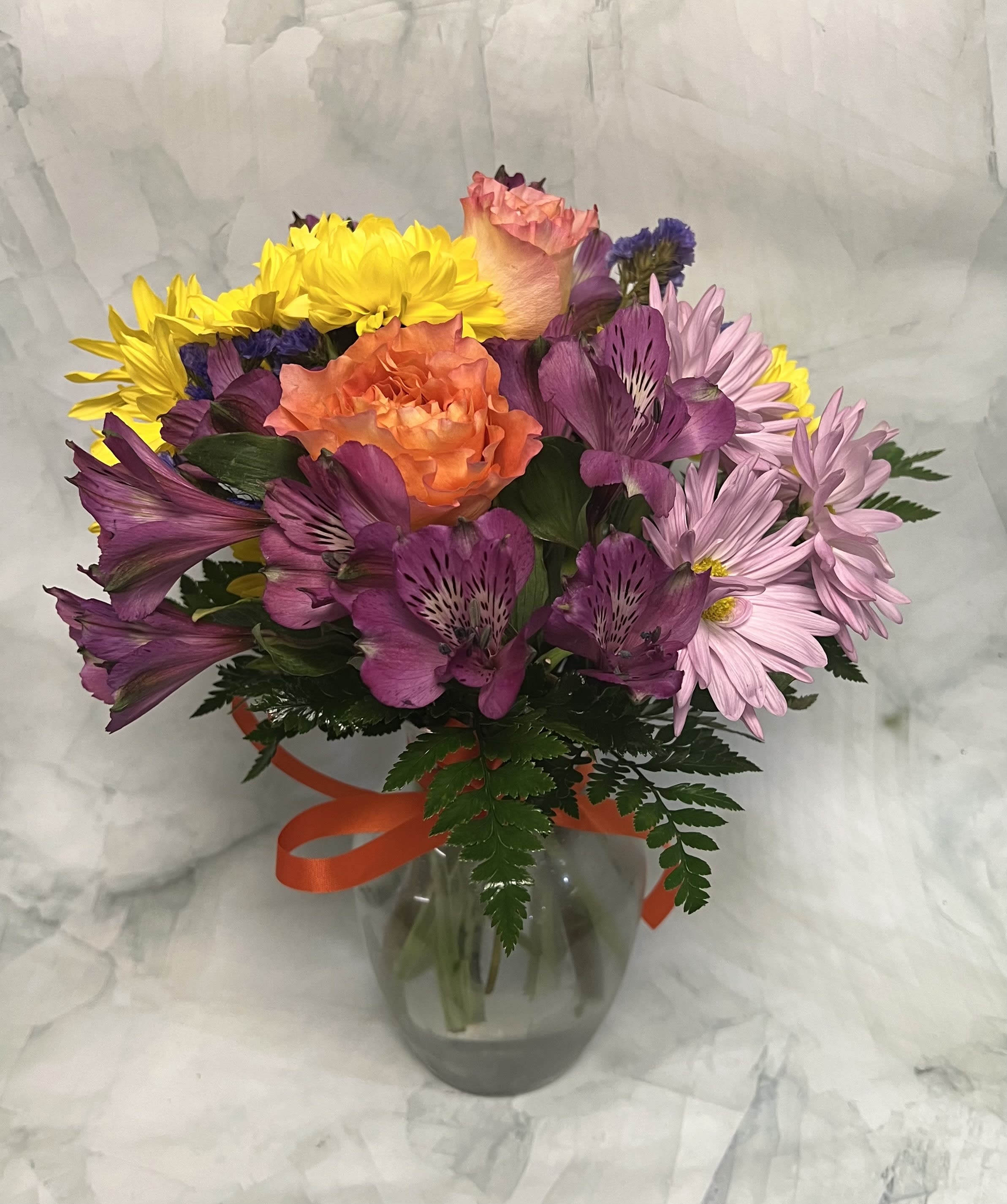 Colorful bouquet of roses, alstroemeria, and daisies in a glass vase