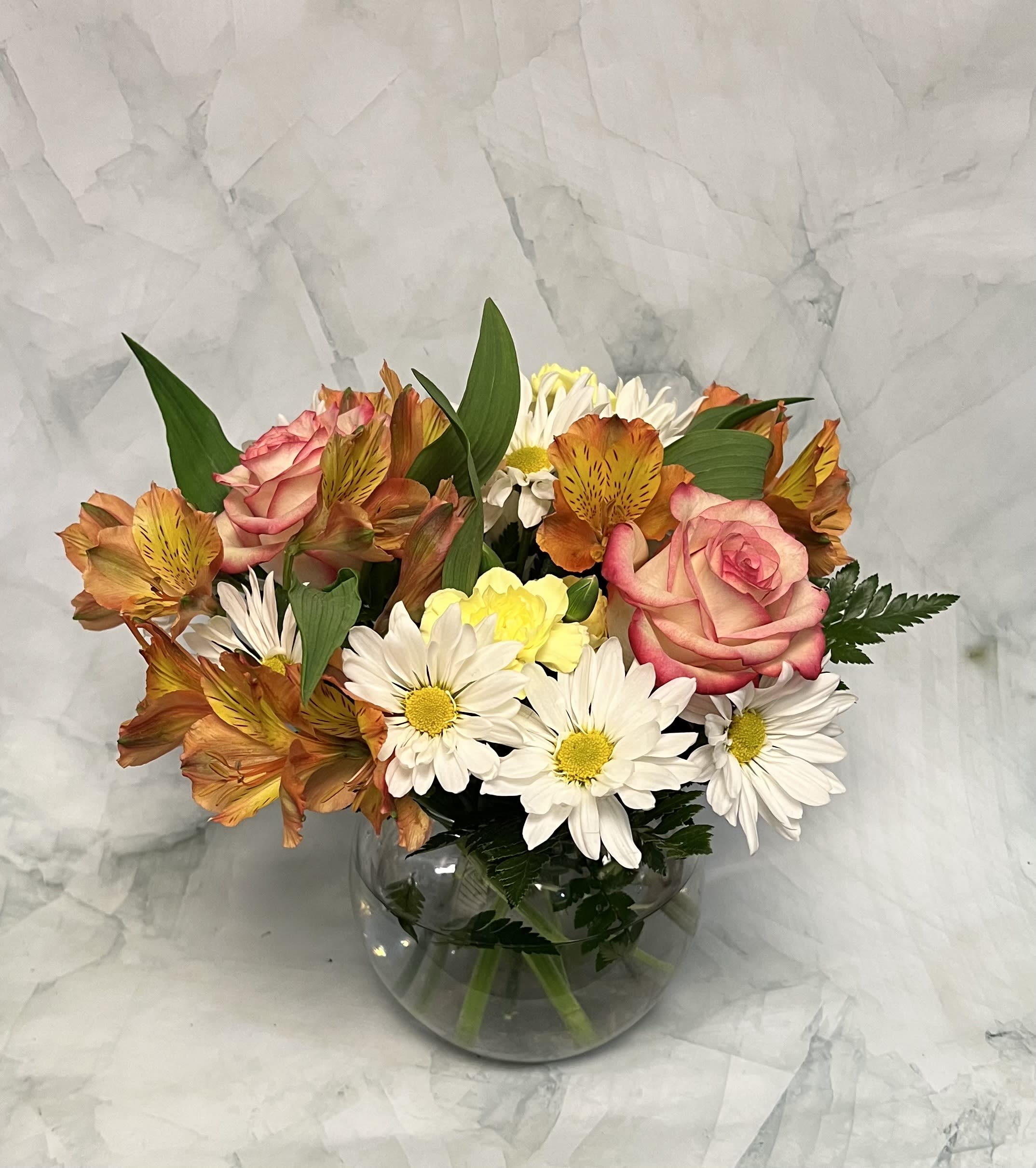 Bouquet of pink roses and white daisies in a round glass vase