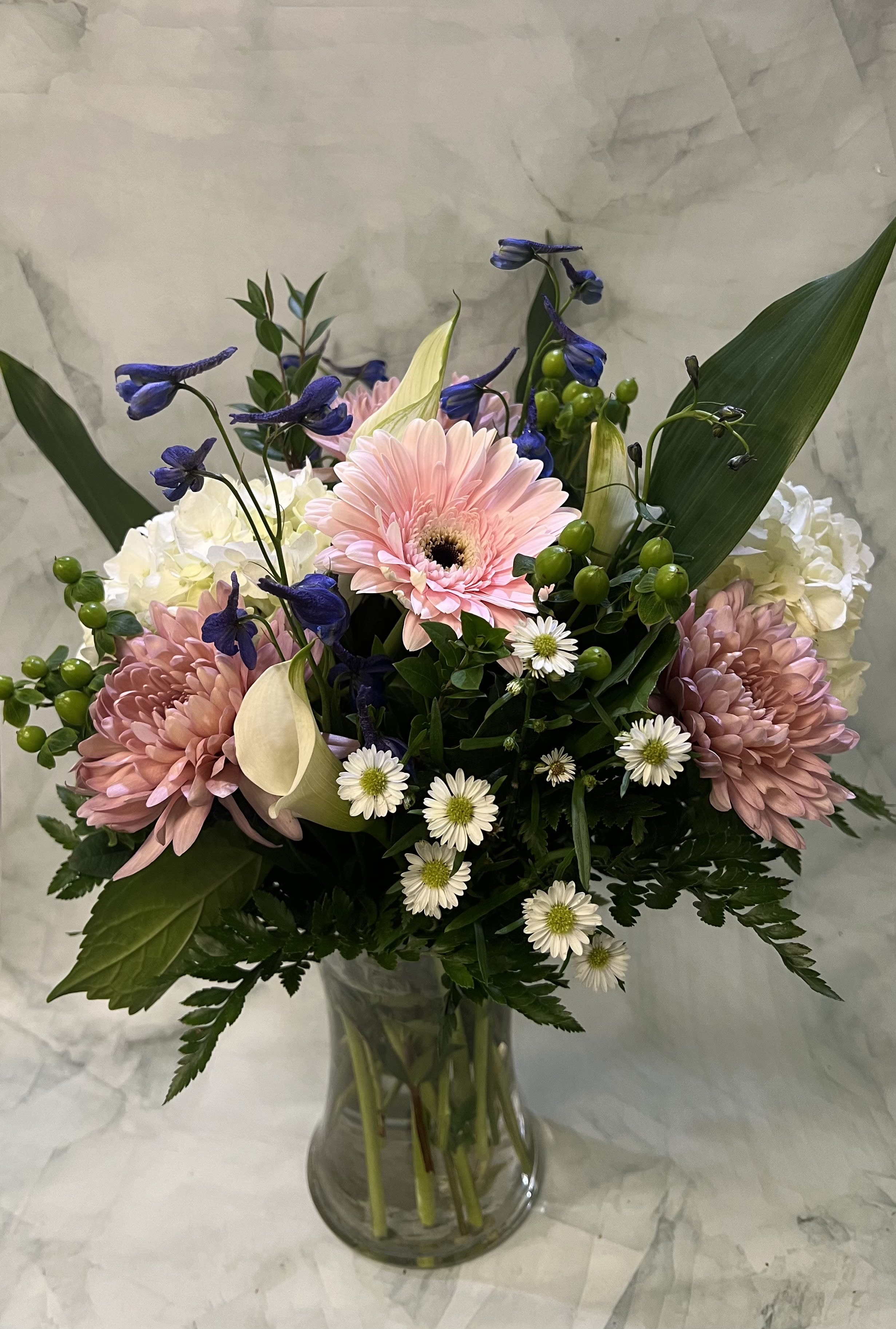 Mixed bouquet in a clear glass vase with pink gerberas and white calla lilies