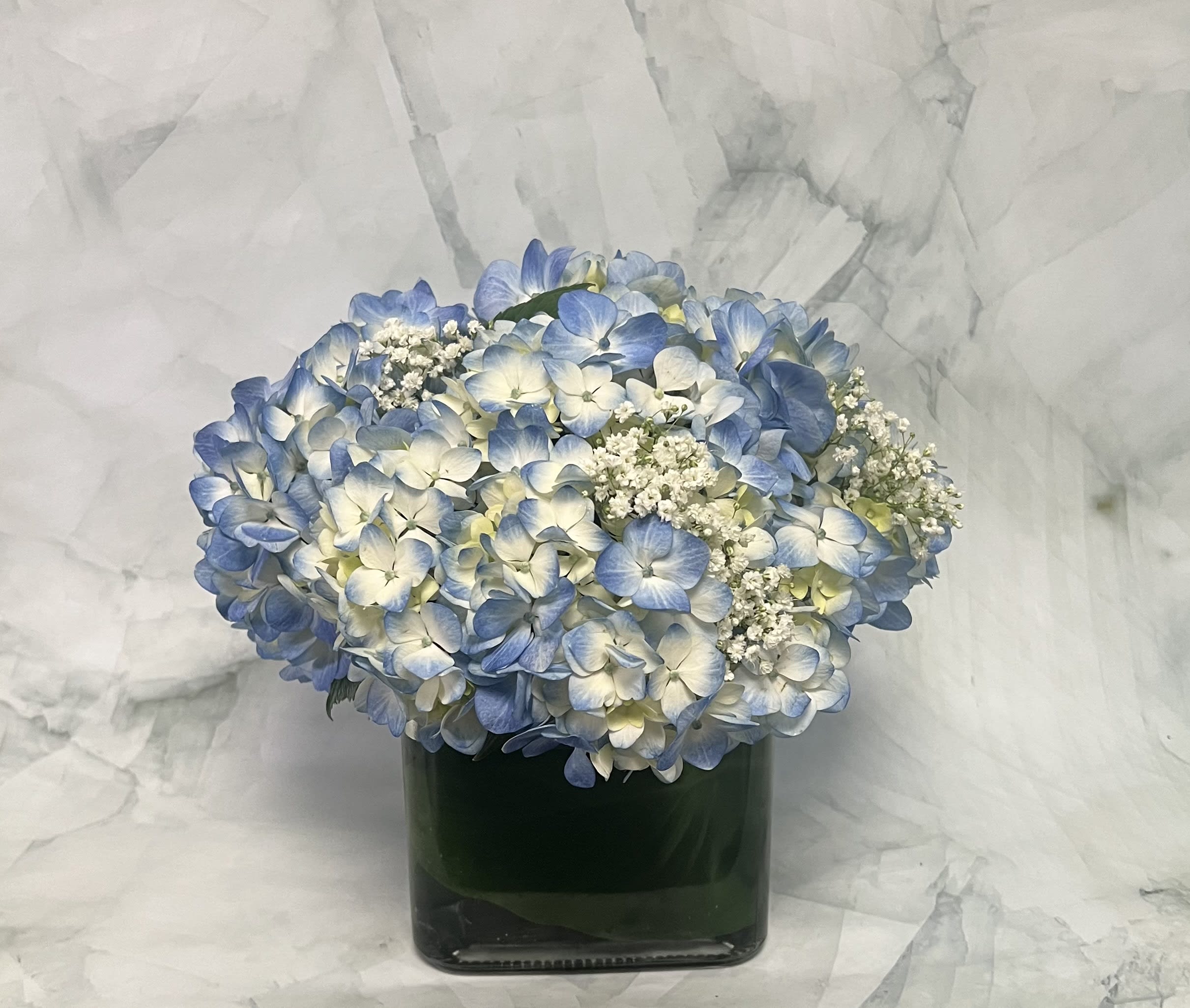 Blue and white hydrangea bouquet in a dark glass vase