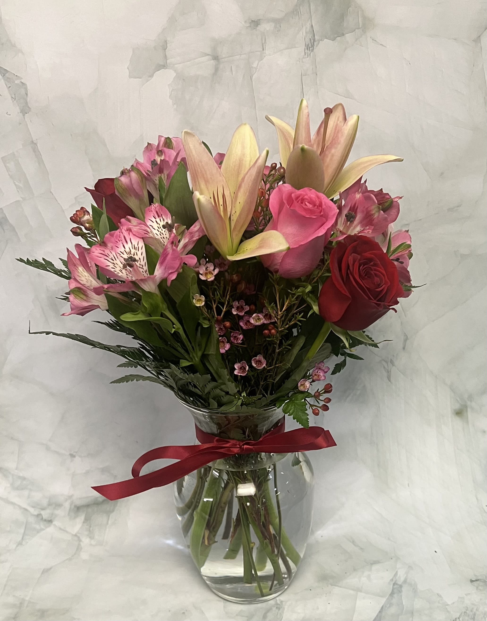 Bouquet of pink lilies, roses, and alstroemeria in a glass vase