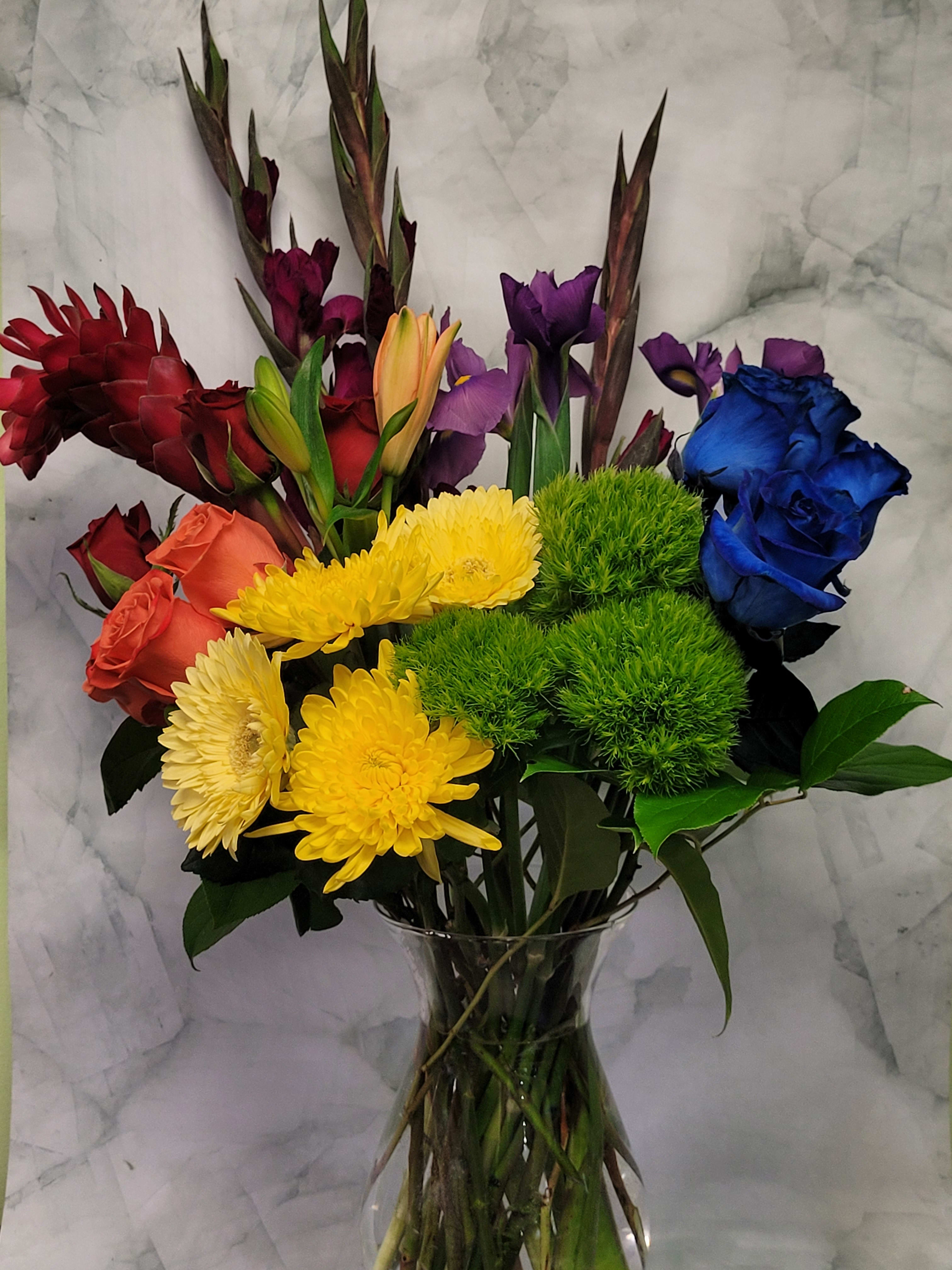 Colorful mixed bouquet in a clear glass vase with roses, chrysanthemums, and lilies