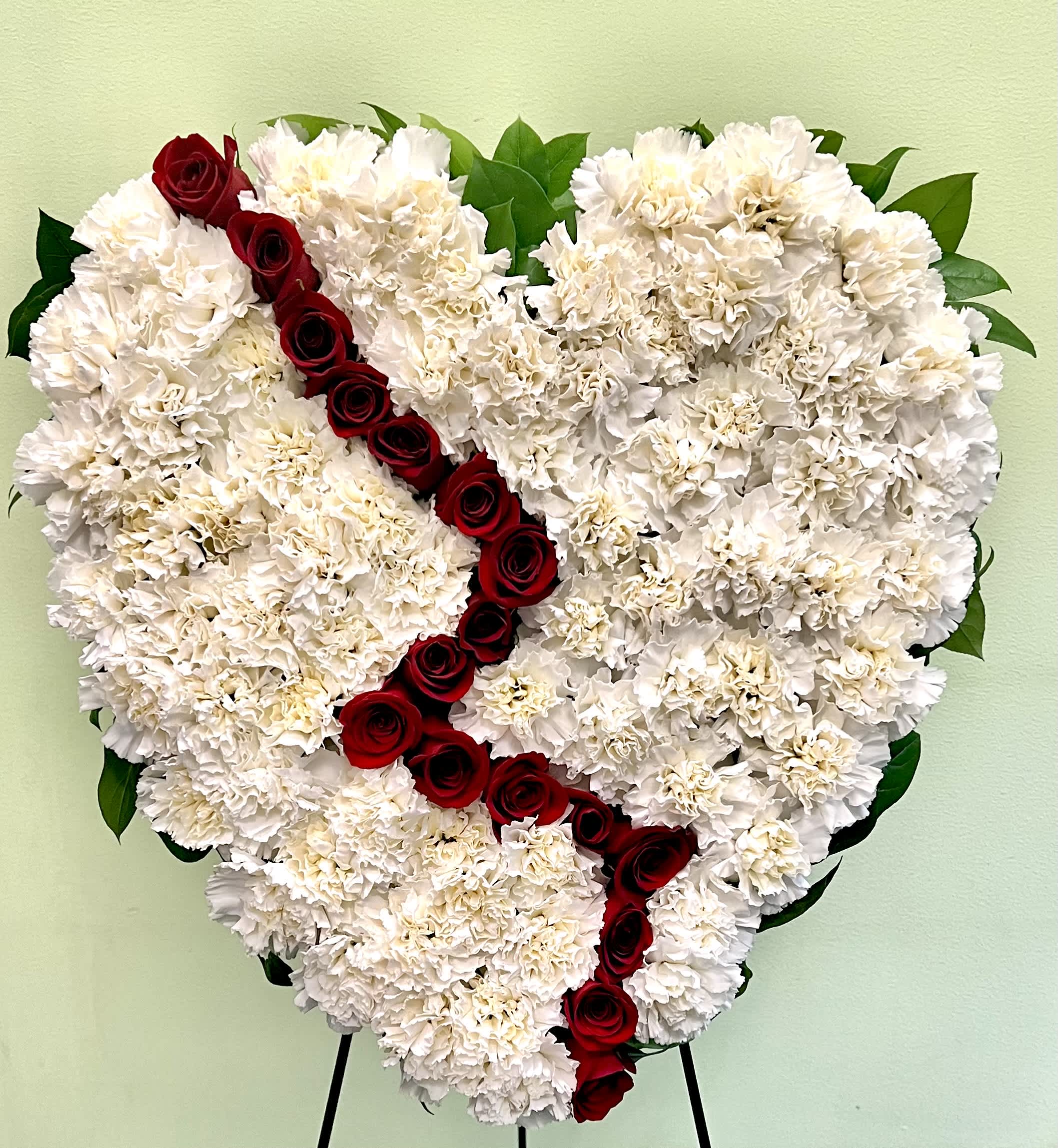 Heart-shaped white carnation arrangement with a diagonal line of red roses