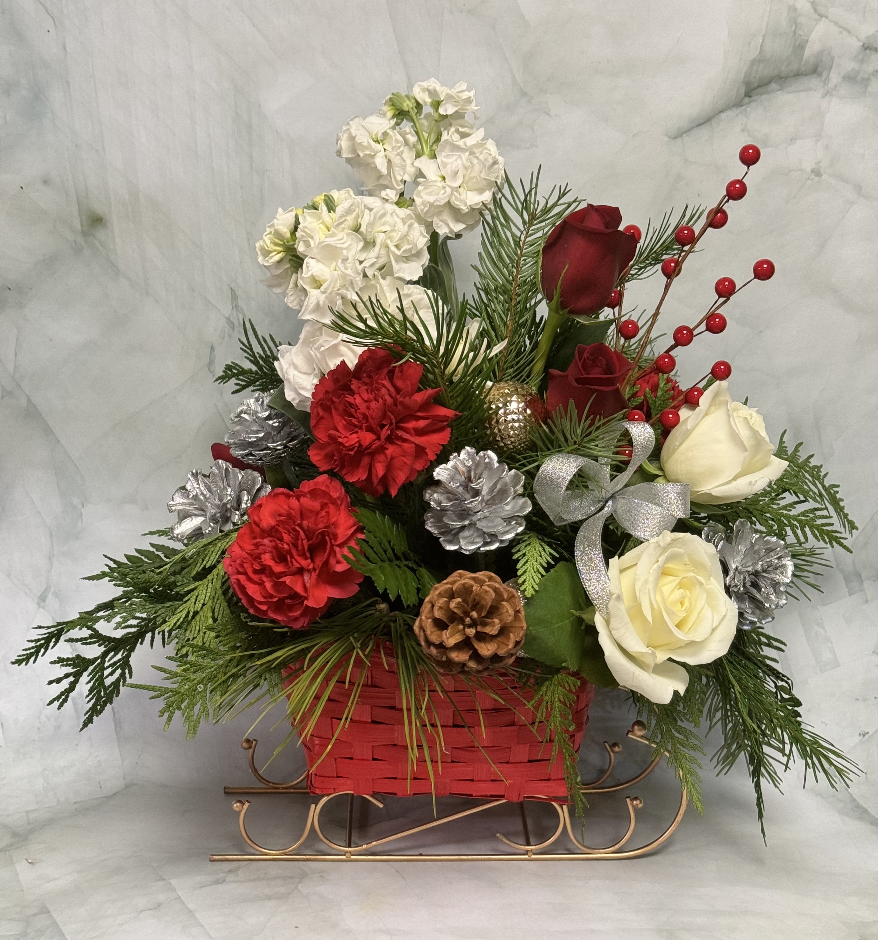 Holiday floral arrangement in a red basket with roses and carnations
