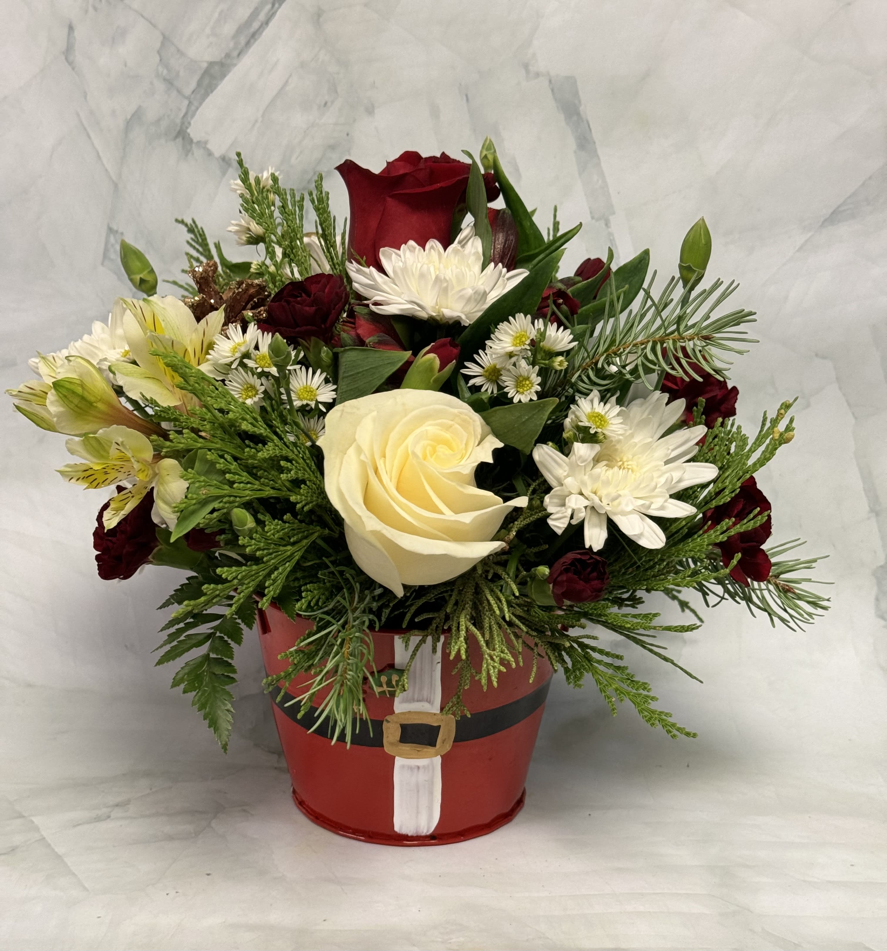 Red and white flower arrangement in a Santa-themed container