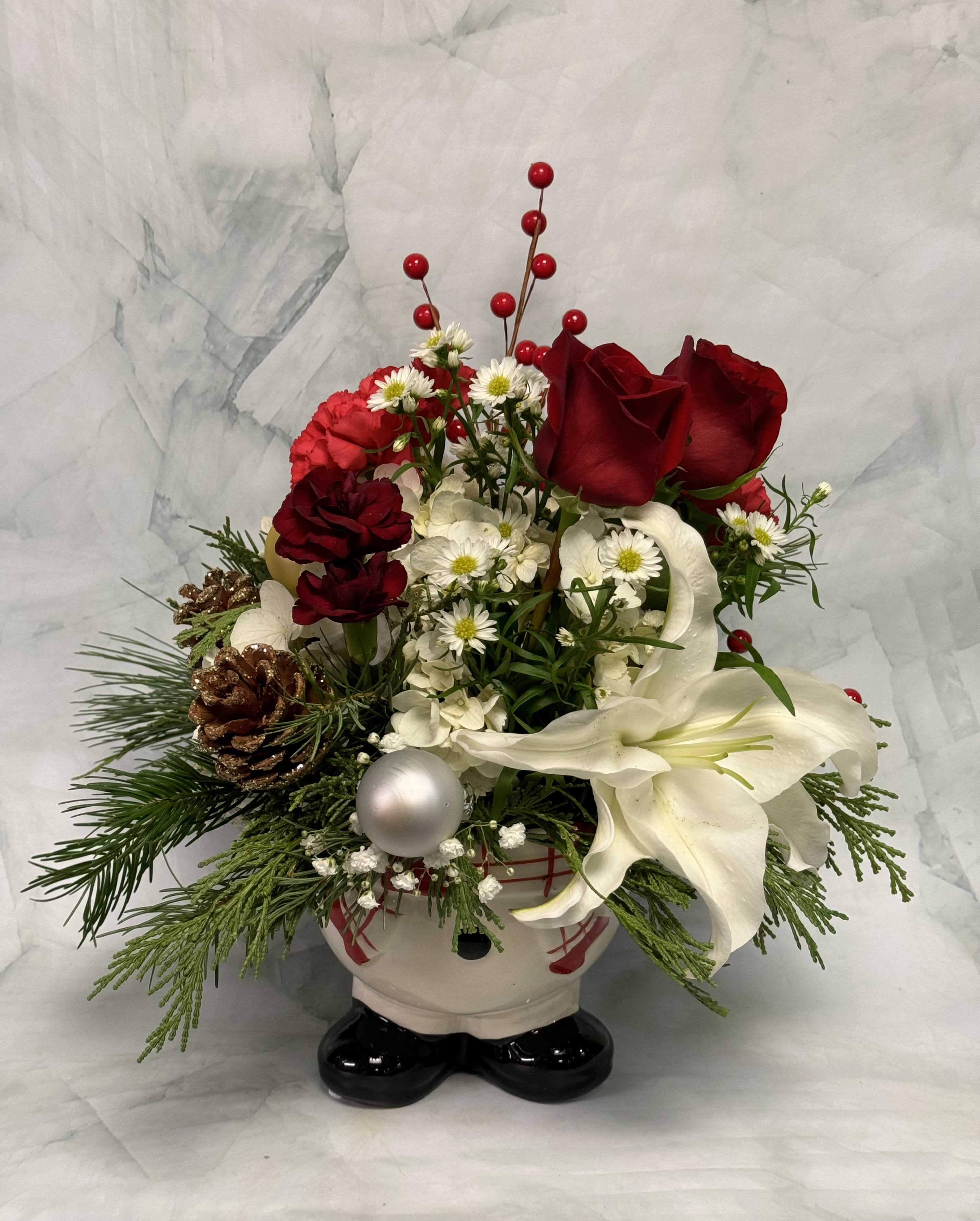 Holiday floral arrangement in a Santa-shaped container with red roses and white lilies