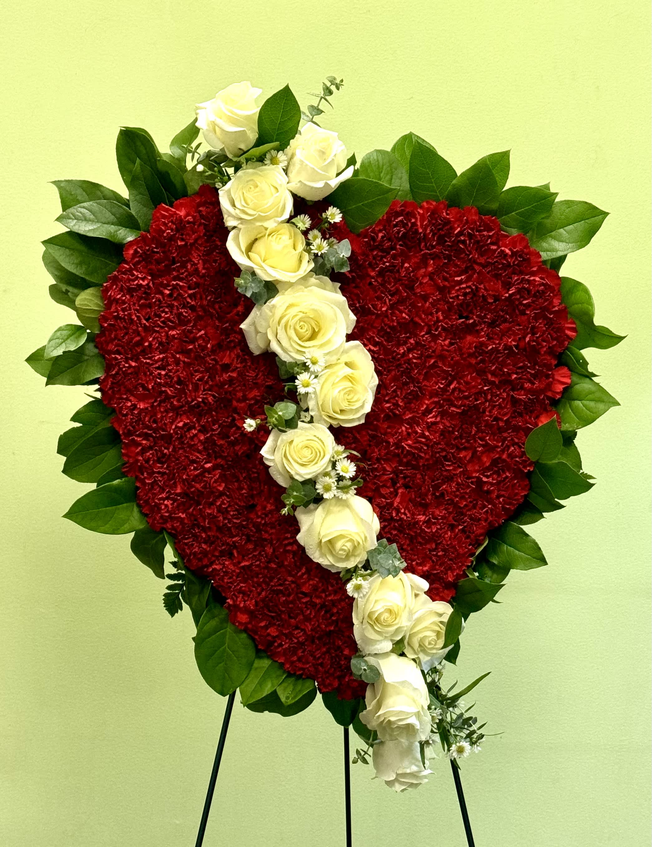 Heart-shaped red floral tribute with white roses on a stand