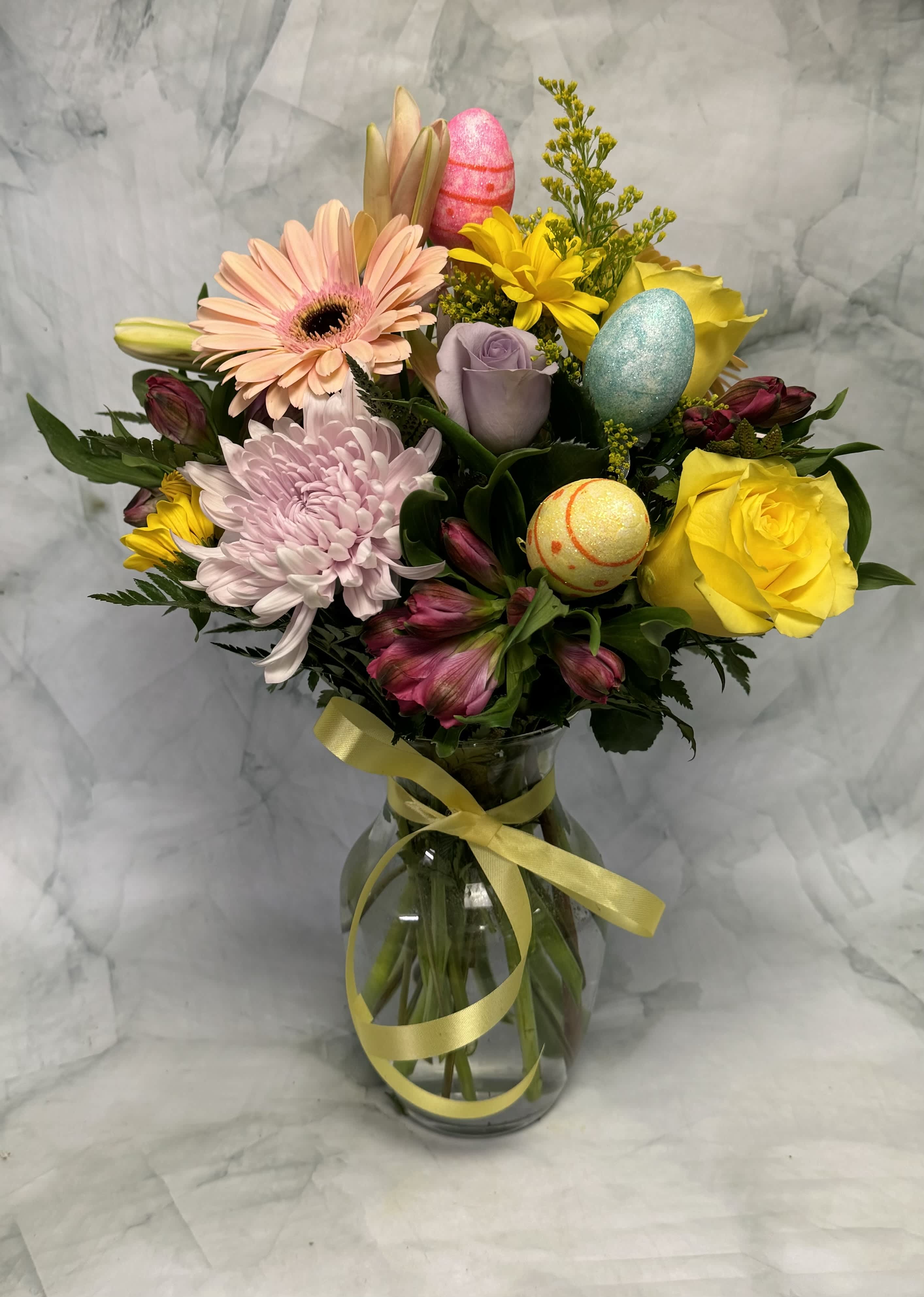 Mixed bouquet in a glass vase with pastel flowers and decorative eggs