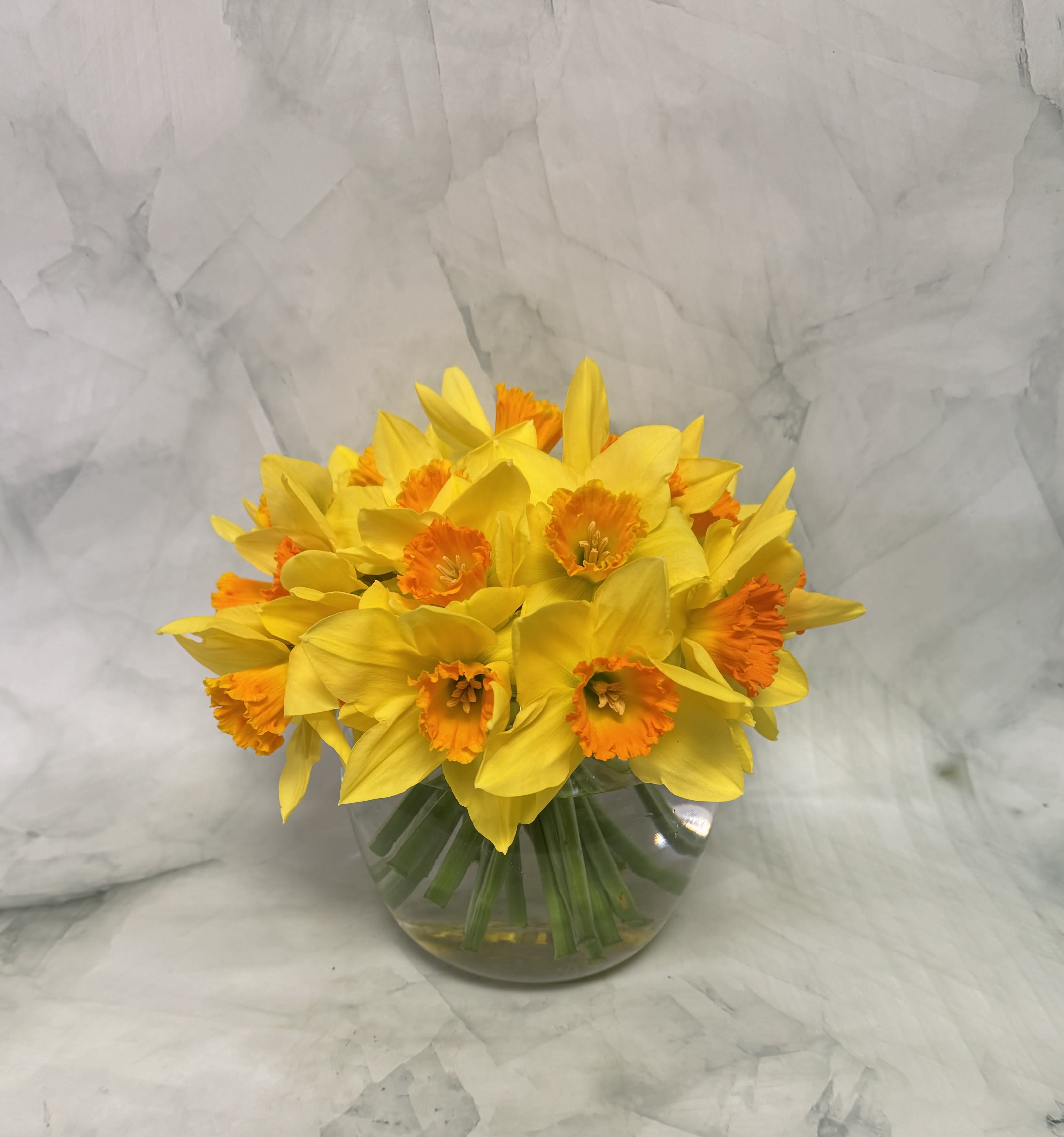 Yellow daffodils with orange centers in a clear glass vase