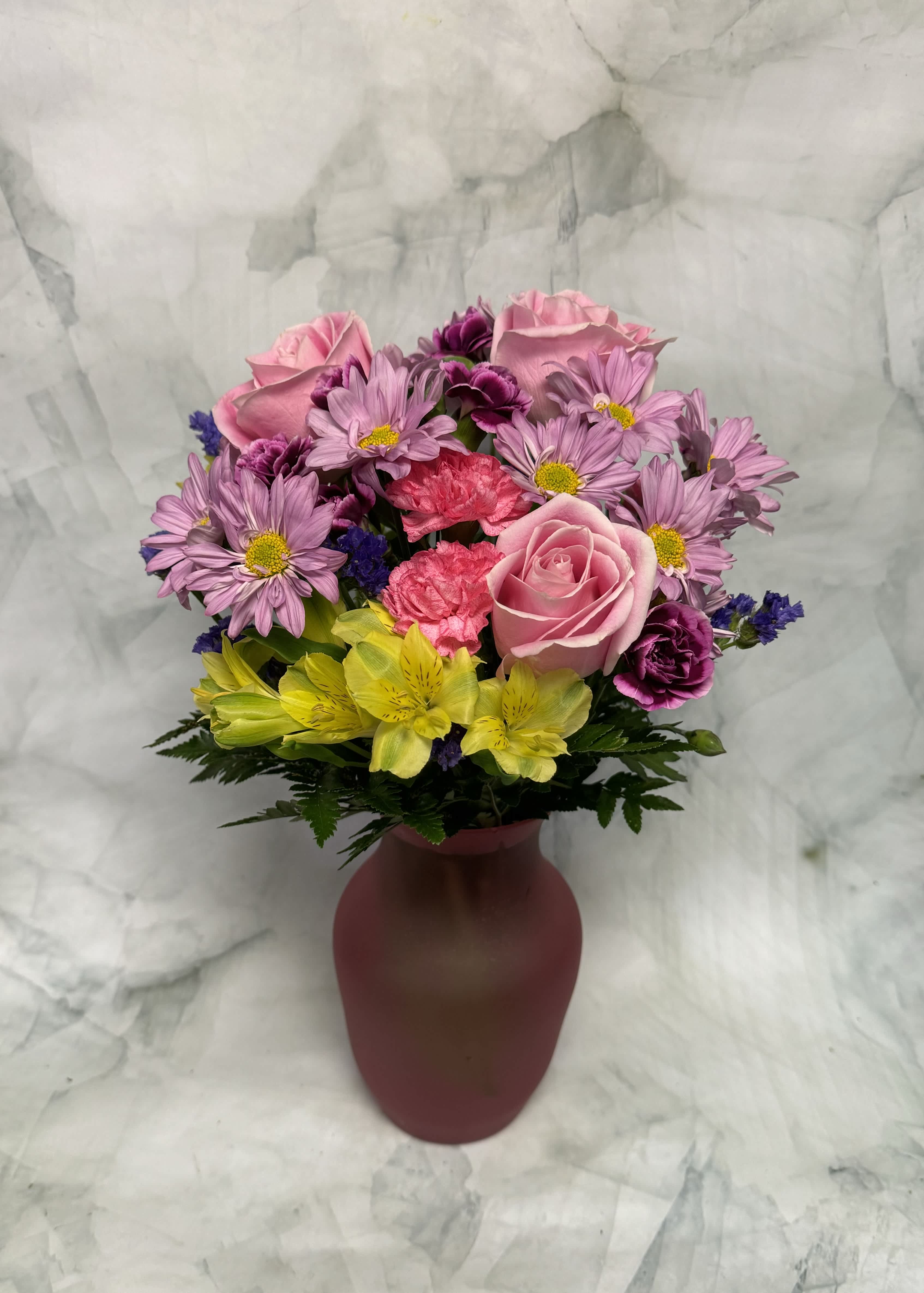 Pink and purple mixed bouquet in a burgundy vase