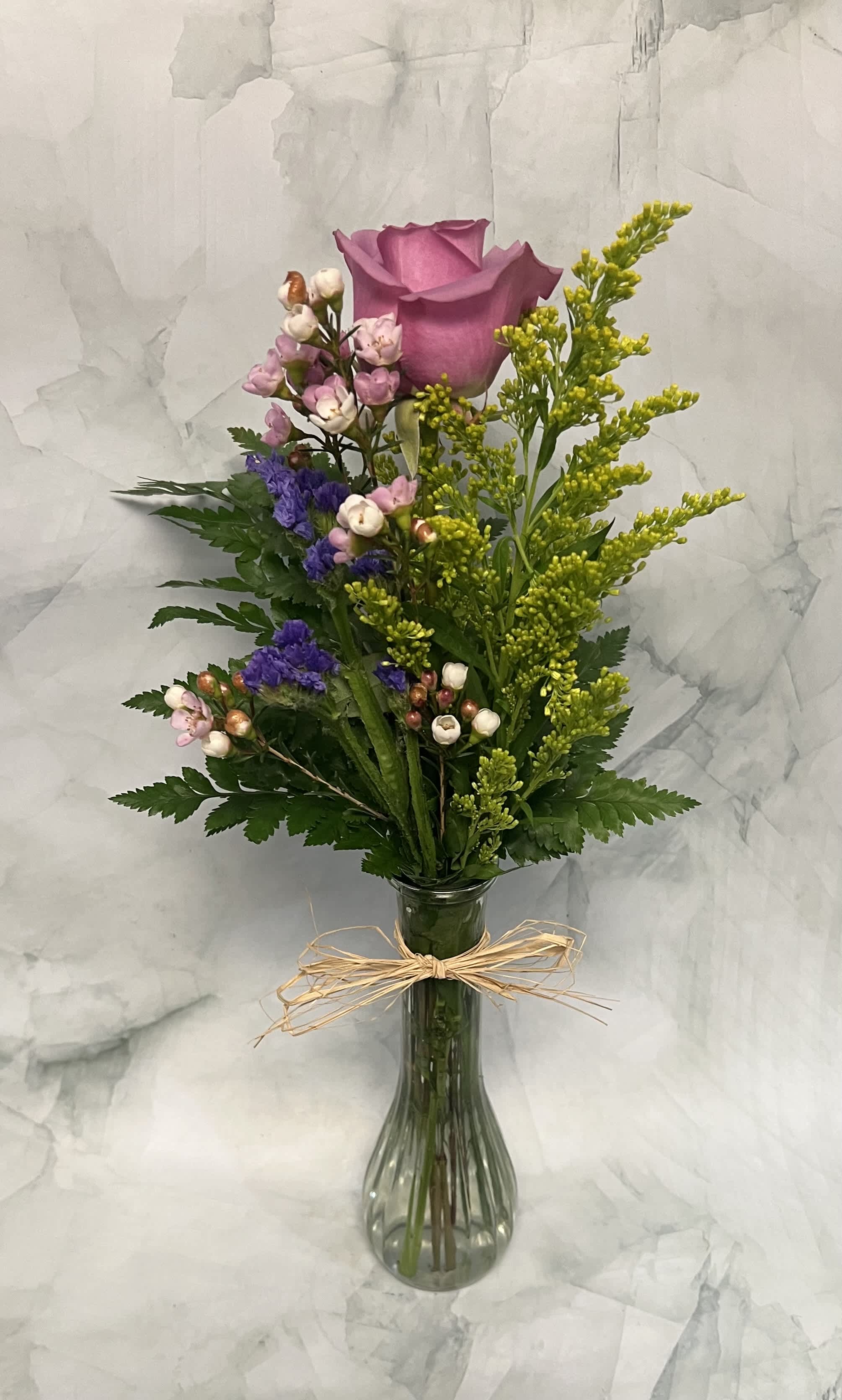 Pink rose bouquet in a clear glass vase with small purple and white flowers