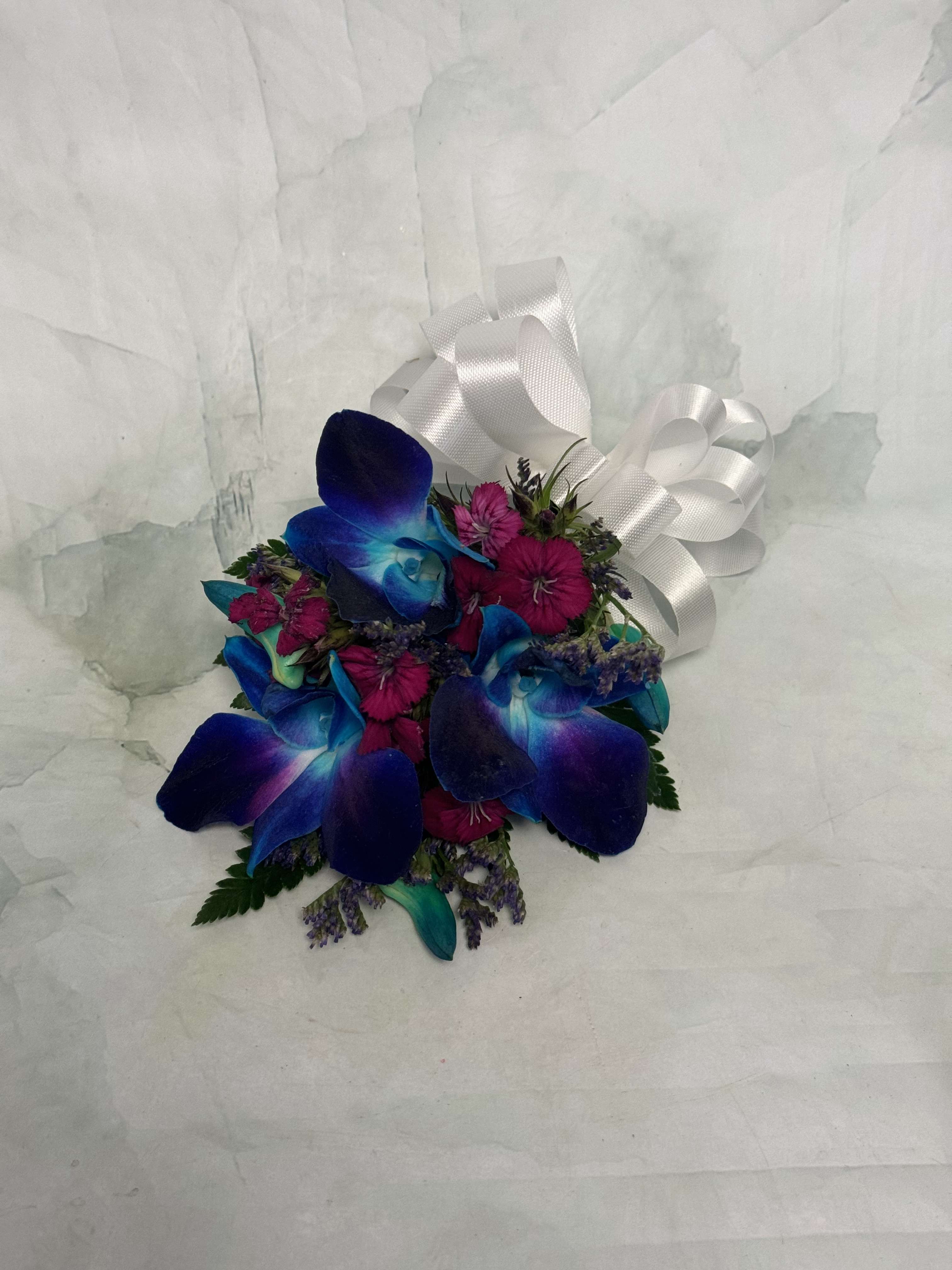 Small bouquet of blue orchids and pink flowers with a white ribbon