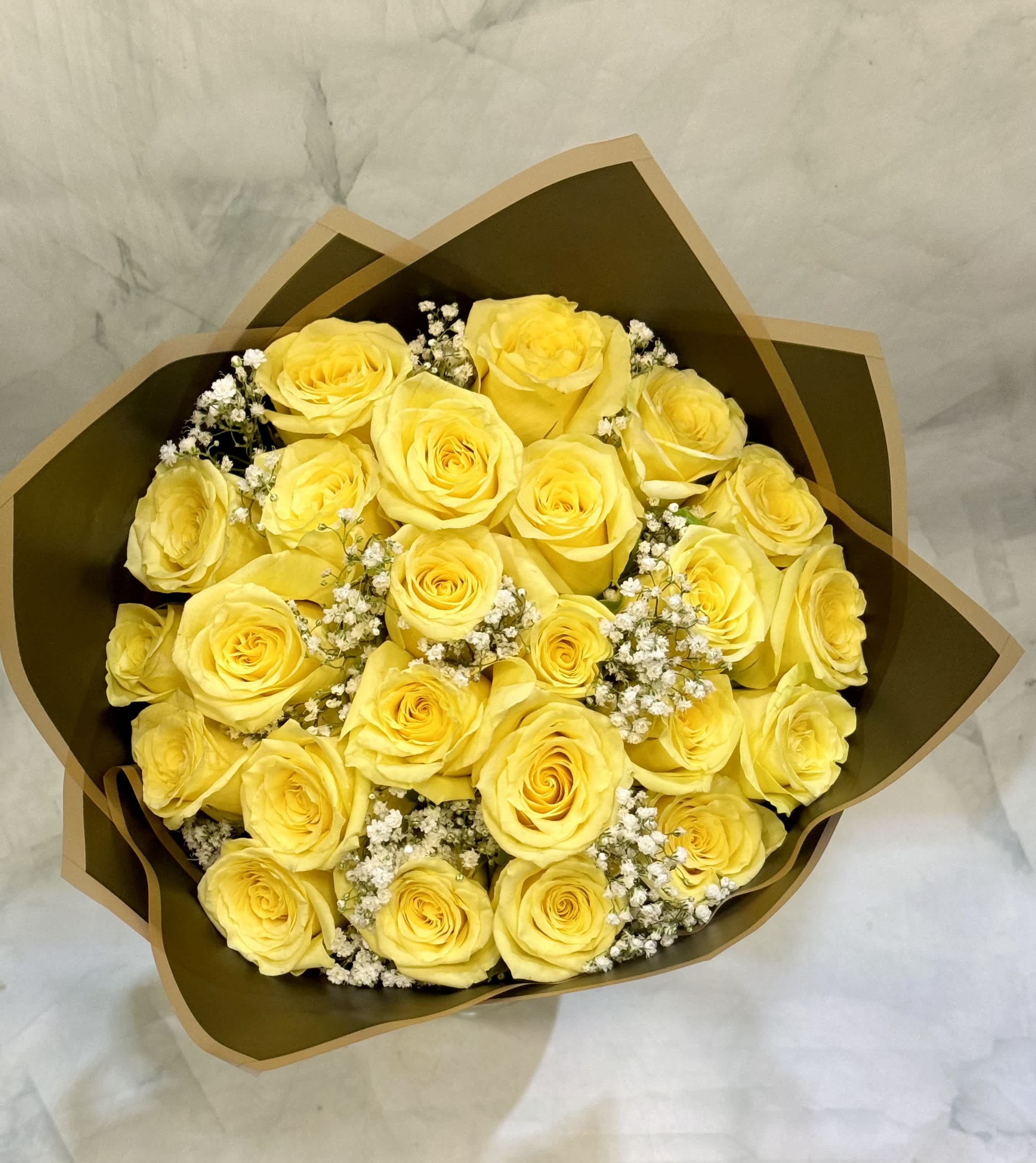 Bouquet of yellow roses with white filler flowers in brown wrap