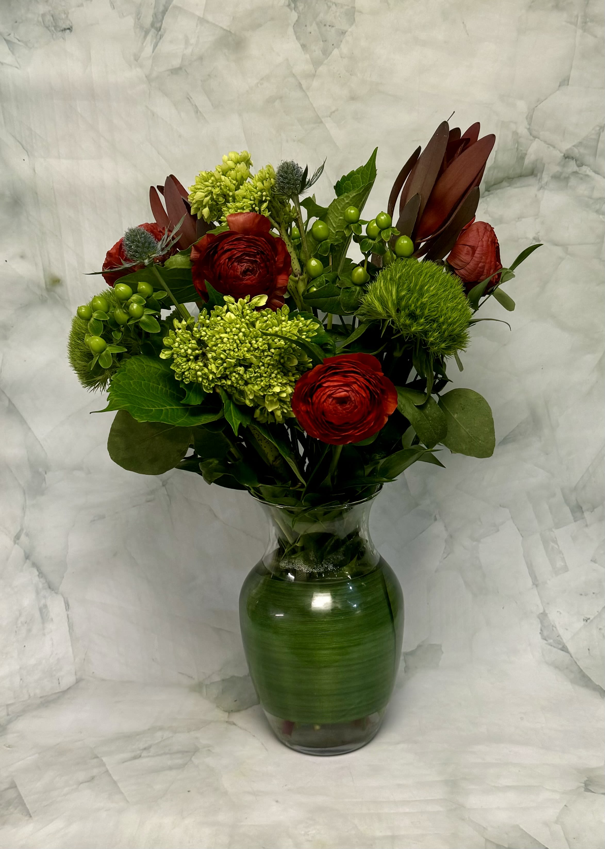 Red and green floral arrangement in a glass vase