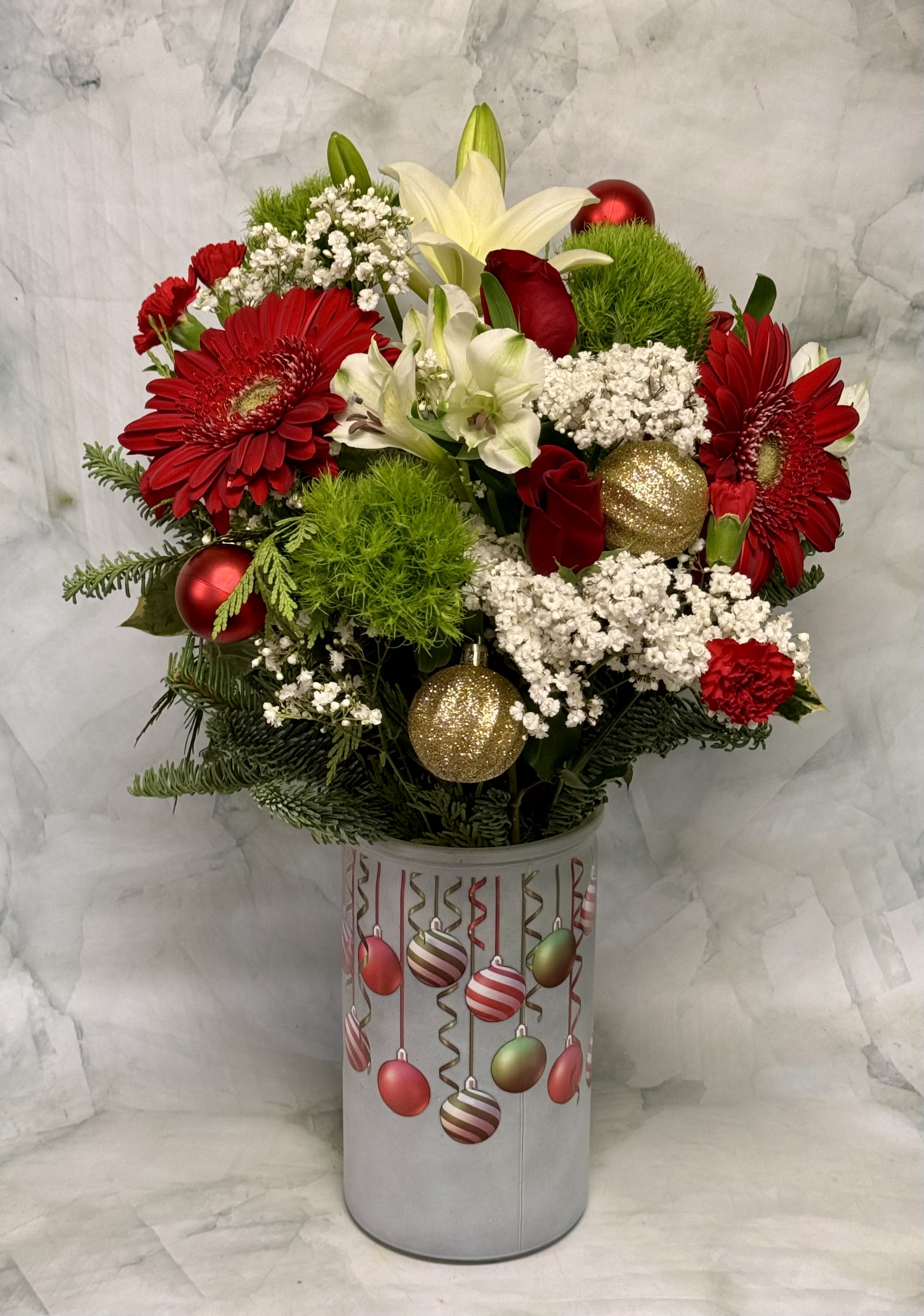 Red and white floral arrangement in a decorated cylindrical container