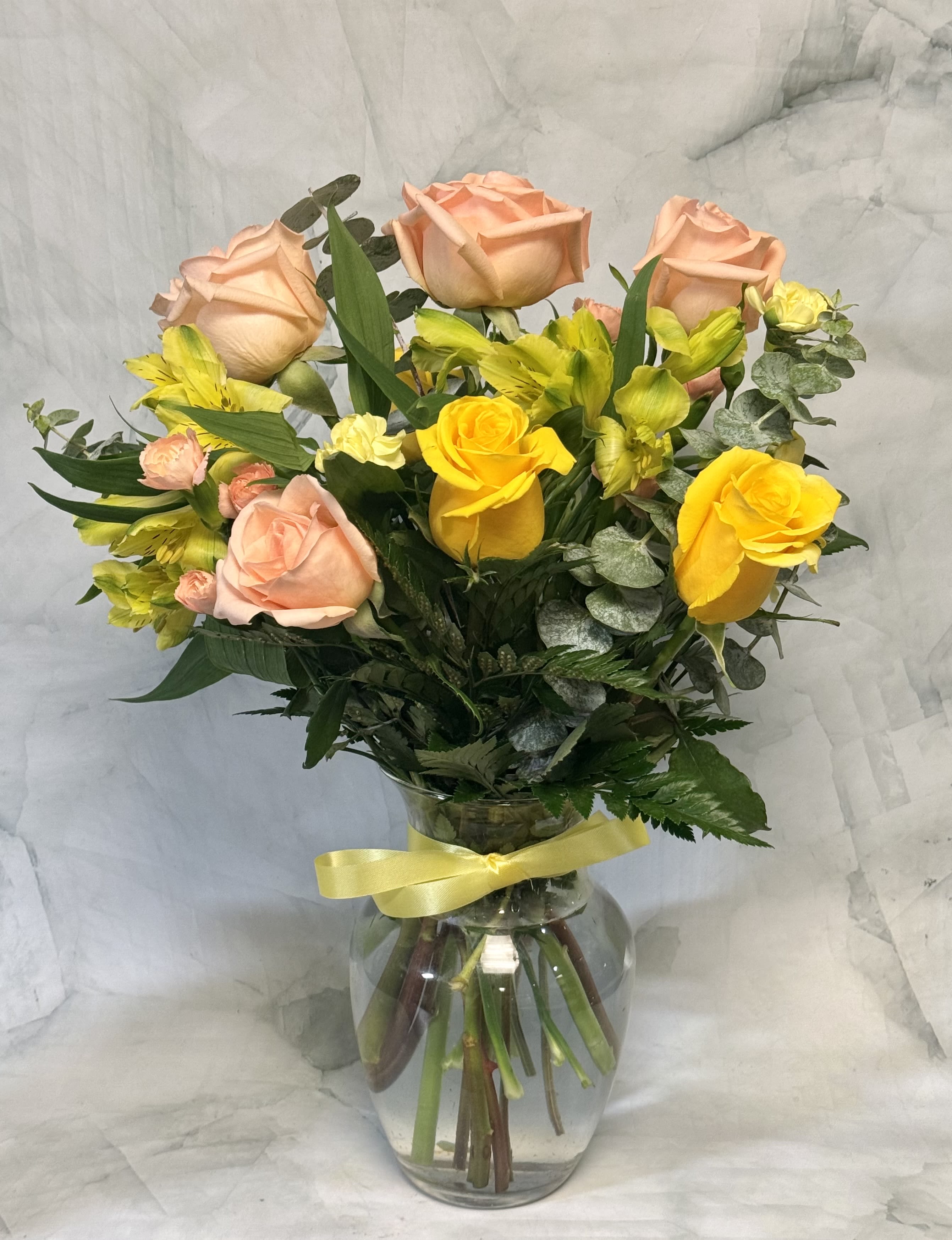 Peach and yellow roses with yellow alstroemeria in a glass vase