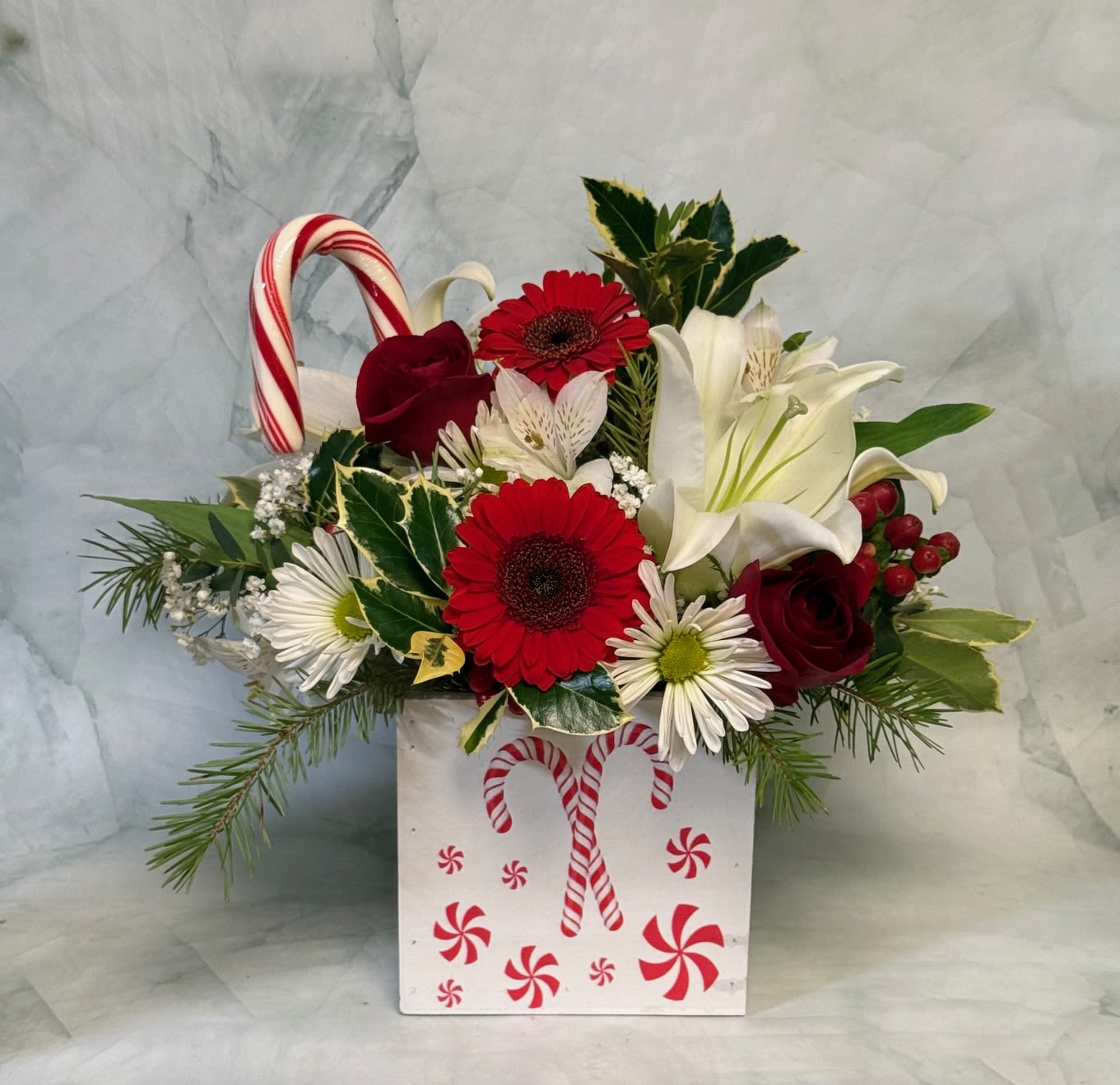 Holiday floral arrangement in a candy cane box with red and white flowers