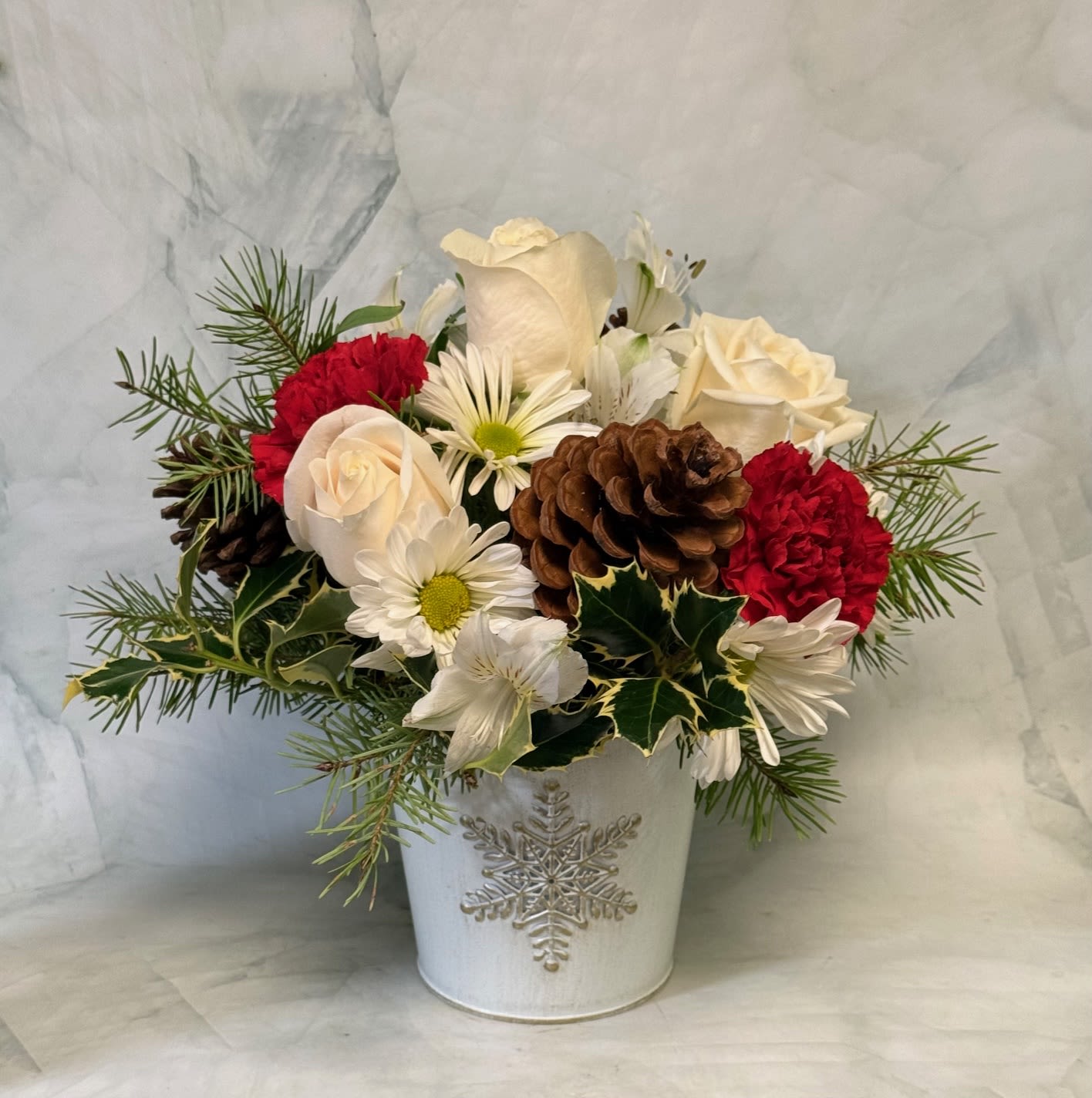 Holiday bouquet of white roses, red carnations, and daisies in a white vase