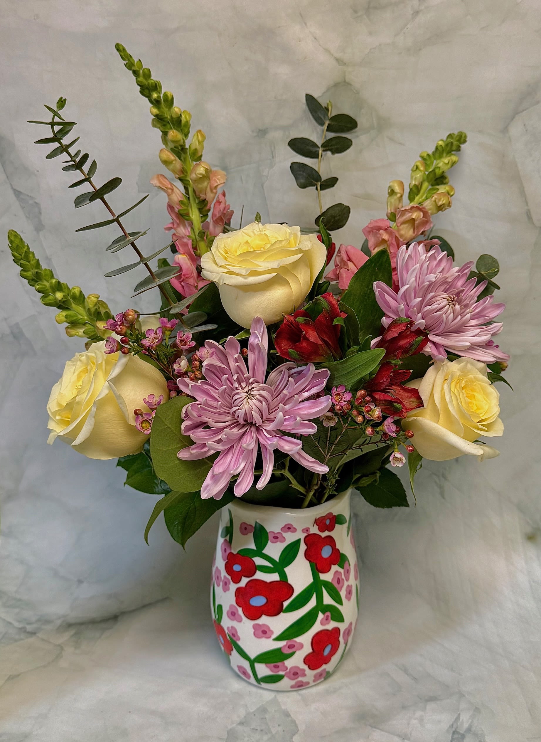 Bouquet of yellow roses, pink chrysanthemums, and red alstroemeria in a painted vase