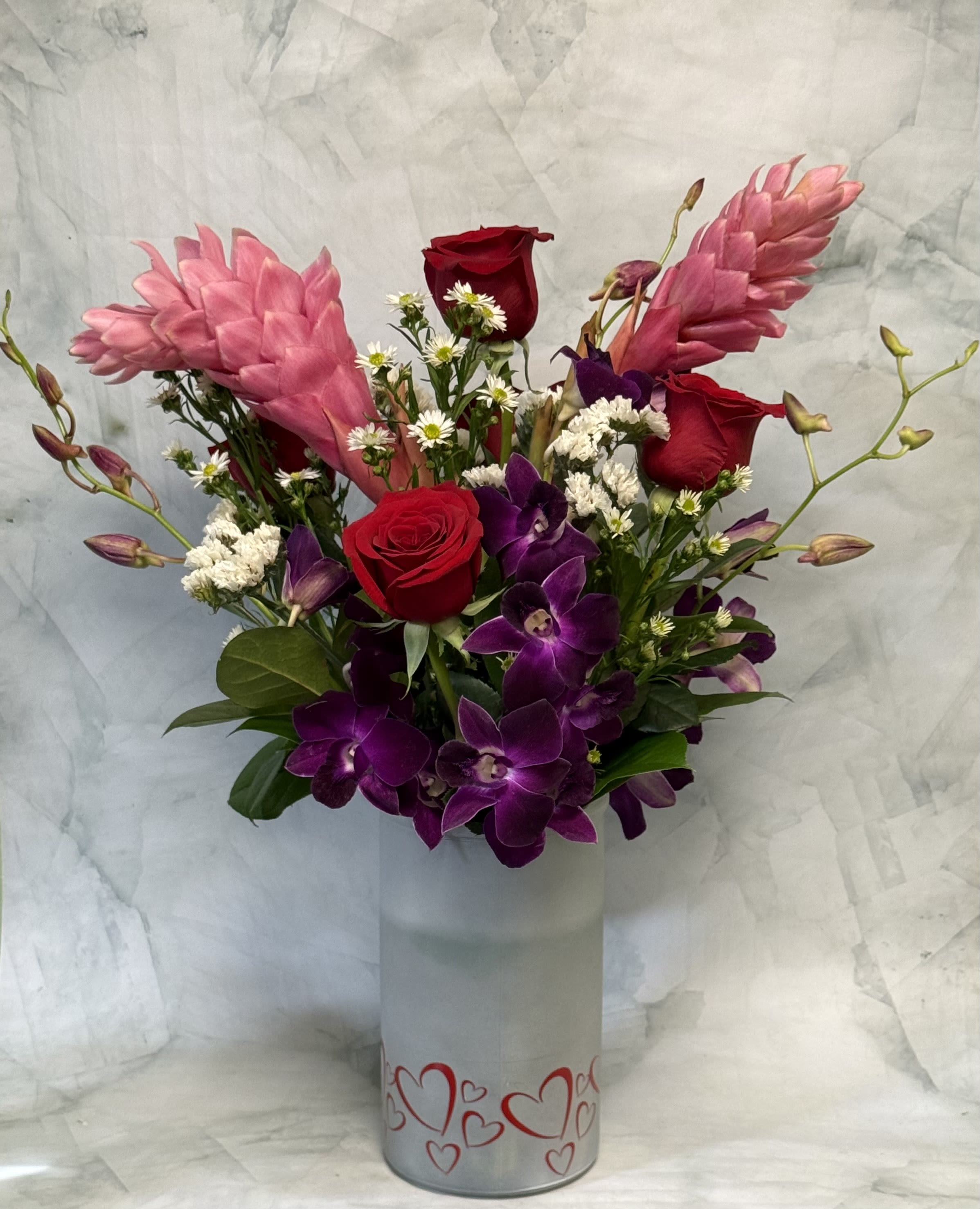 Bouquet of red roses and purple orchids in a heart-decorated vase