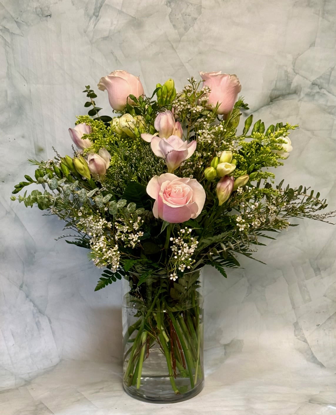 Flirty Freesias - This arrangement is over flowing with an underated flower known as Freesia. This Freesia focused arrangement is filled with other fragrant flowers such as roses, eucalyptus and wax flower.