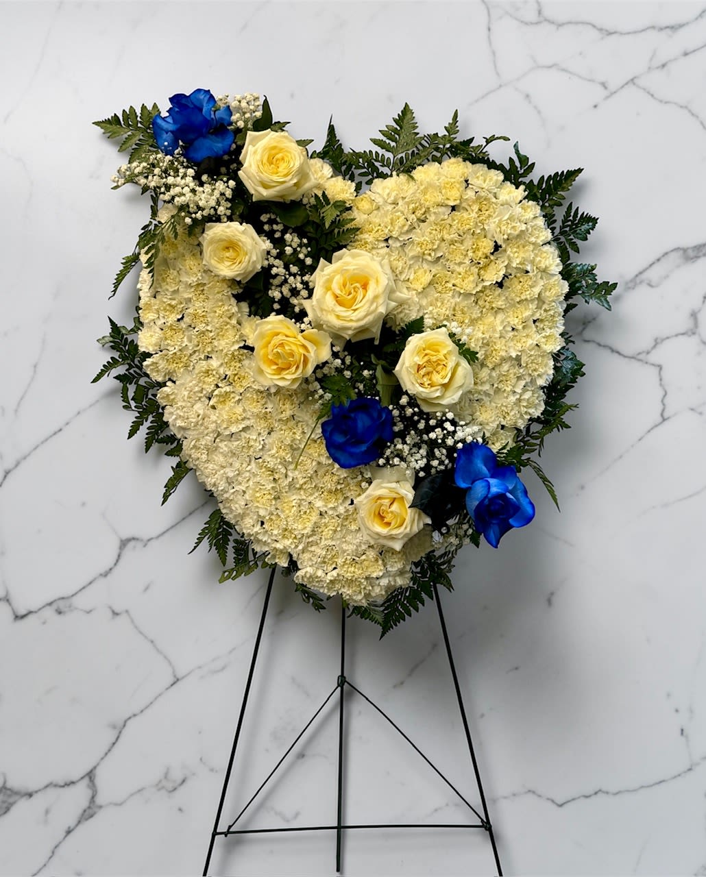 White and Blue Sympathy Heart - This is a white and blue bleeding heart inspired funeral spray. This heart is all white and includes white and blue roses. This is a 24" heart. 