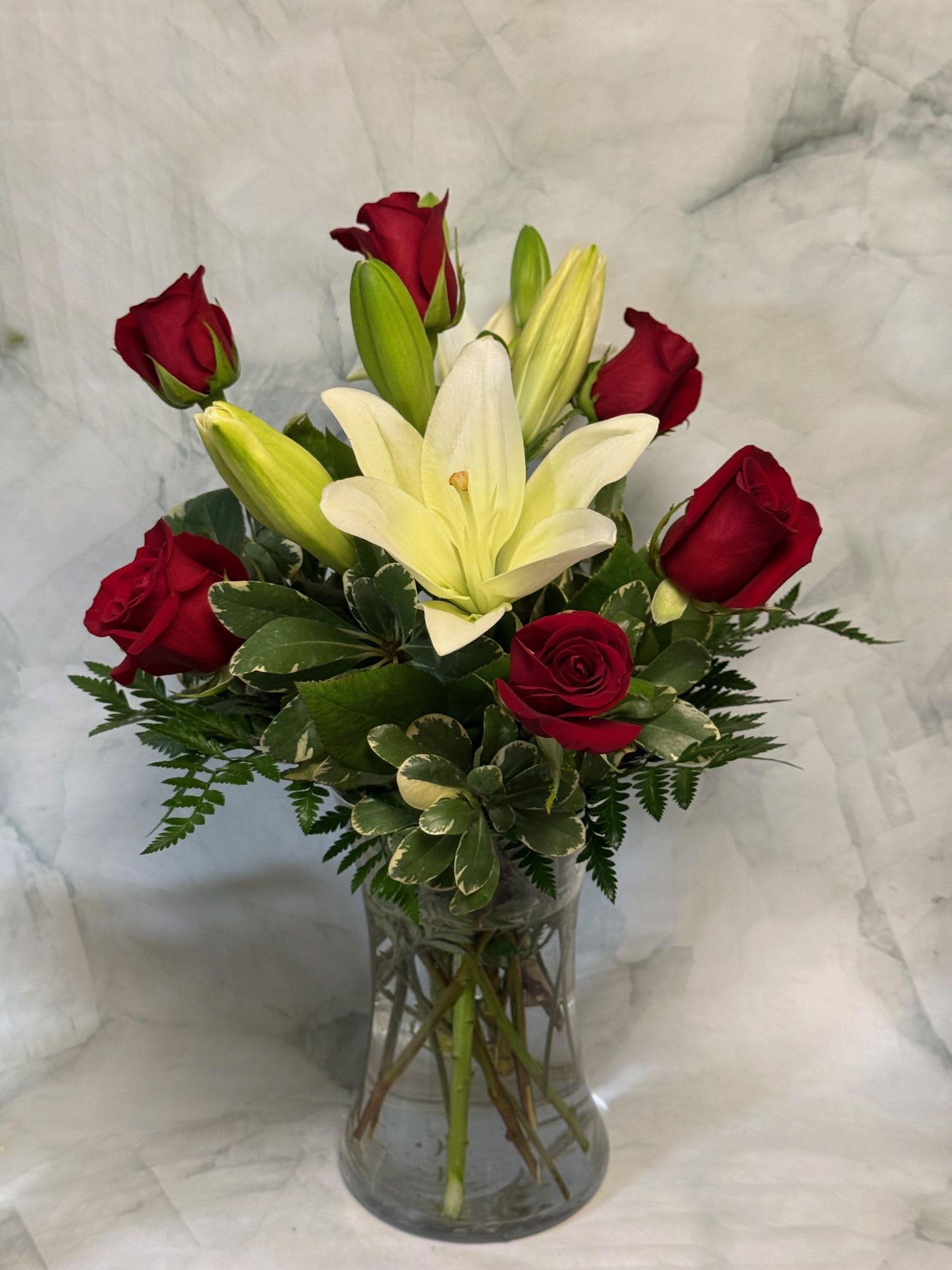 Red roses and white lilies arranged in a clear glass vase