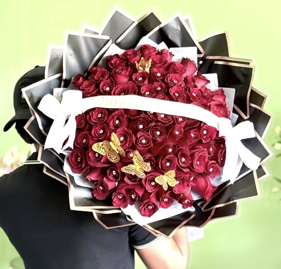 Large bouquet of deep red roses with black wrapping and white ribbon