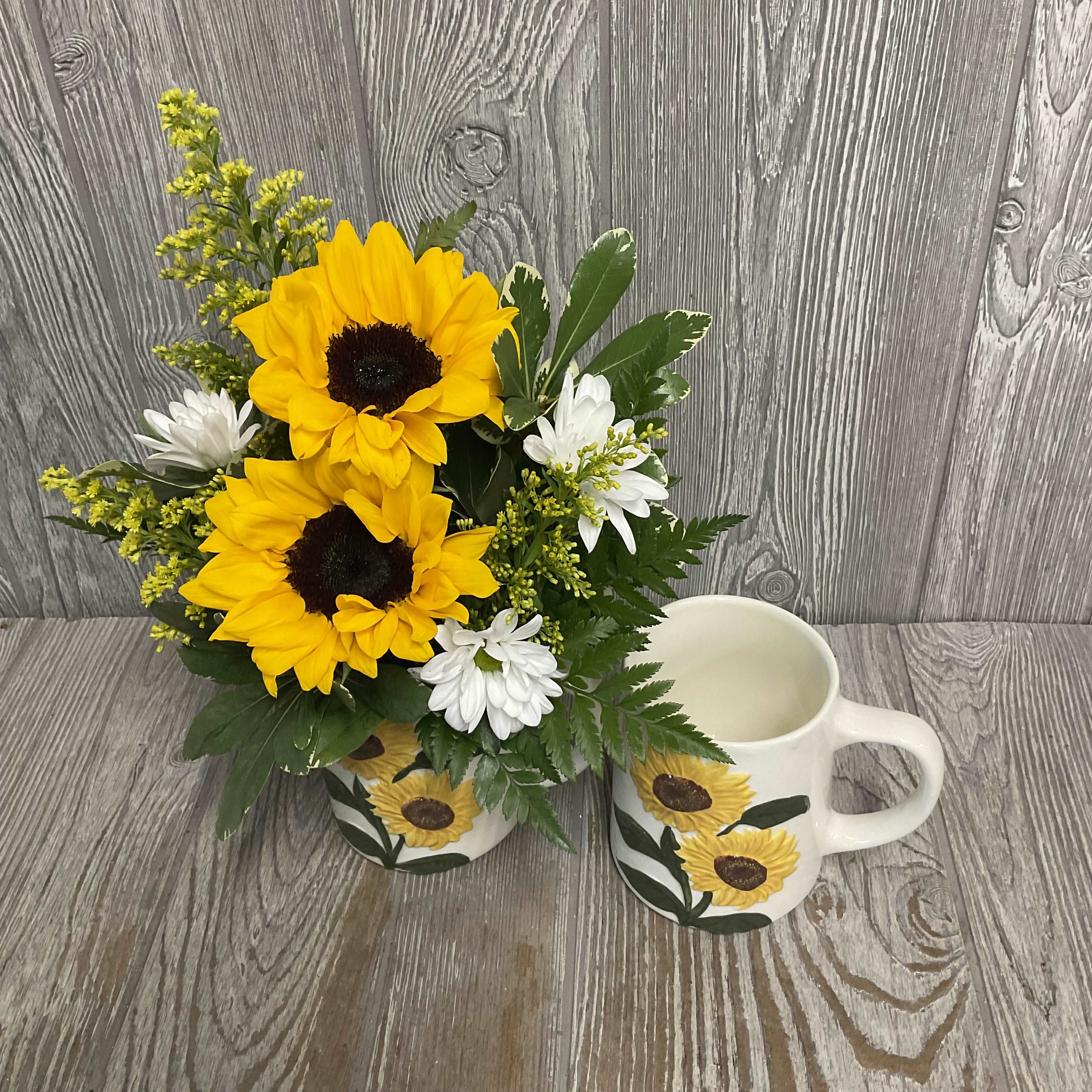 Sunflower bouquet in a painted mug beside a matching sunflower mug