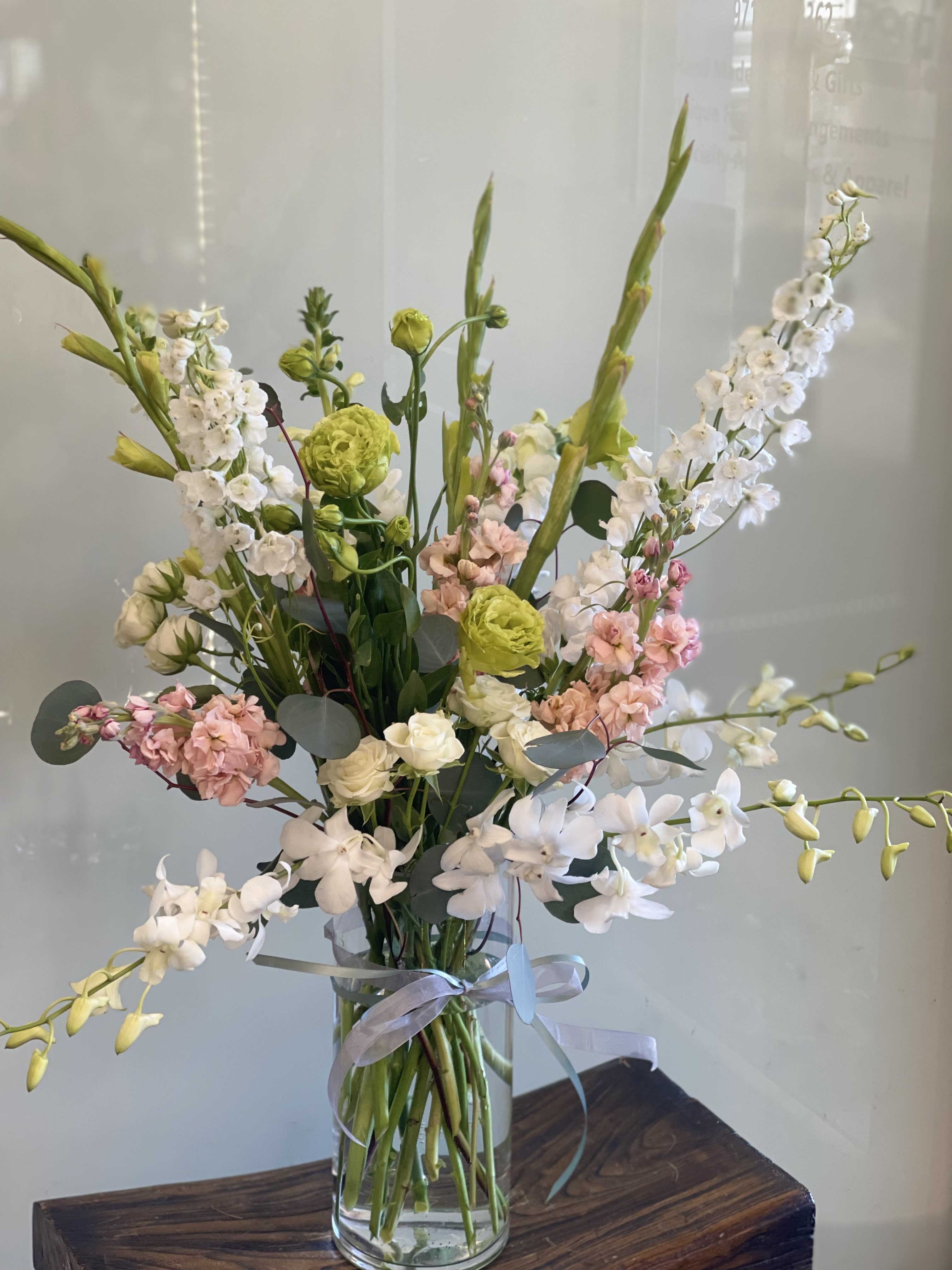 Tall mixed bouquet in a clear glass vase with white, pink, and green blooms