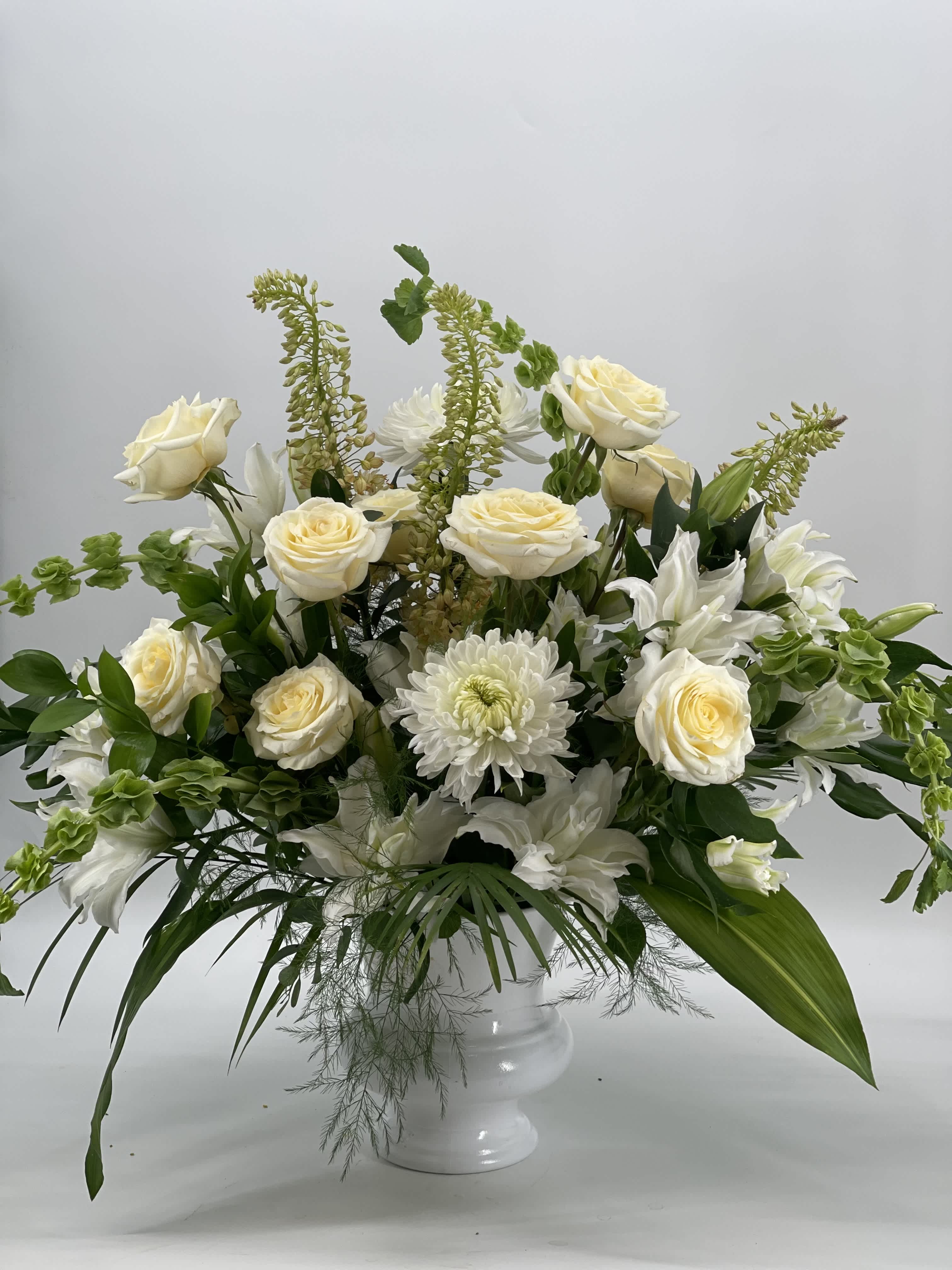 White roses and chrysanthemums in a white pedestal vase