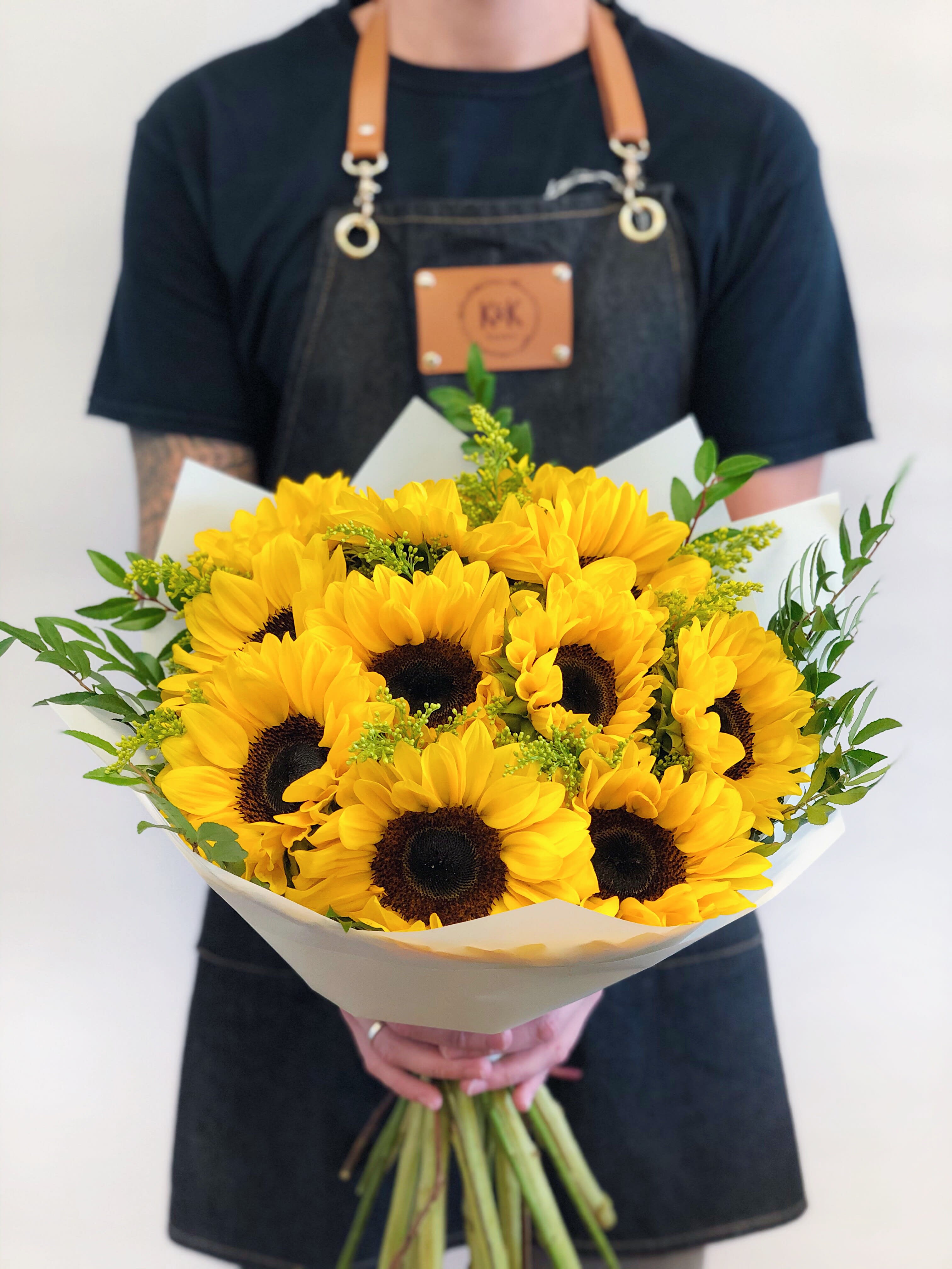 Bouquet of bright yellow sunflowers wrapped in white paper