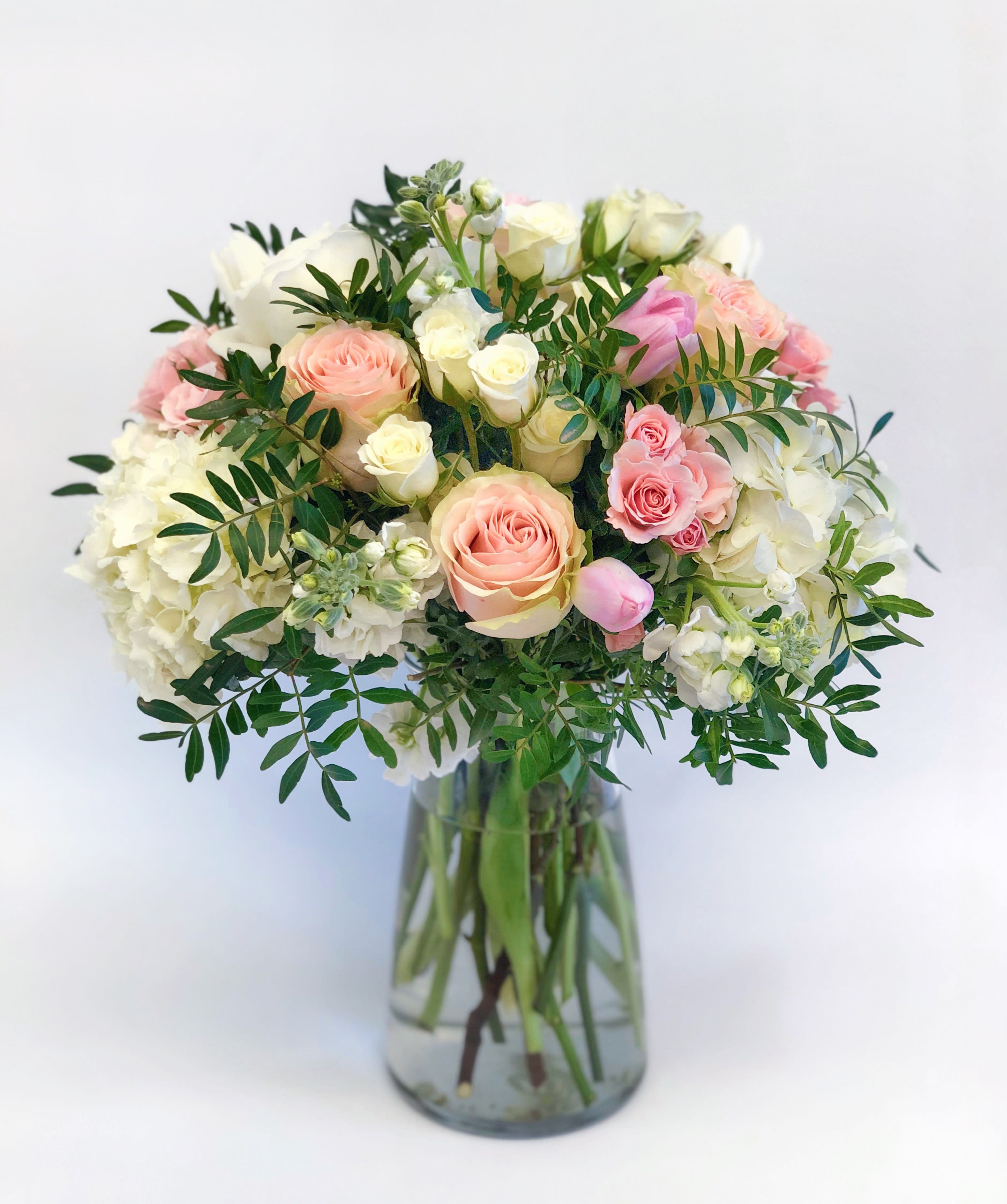 Pink and white roses arranged in a clear glass vase
