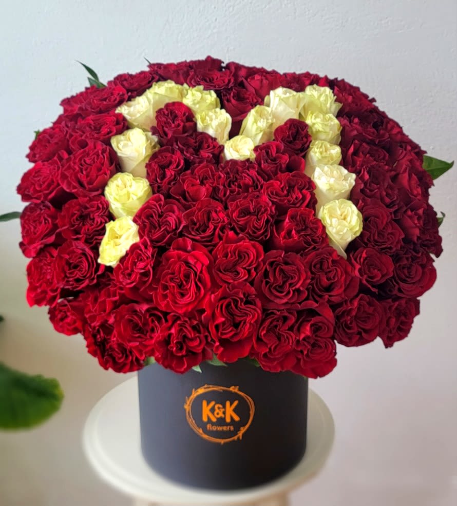 Red and cream roses arranged in a black hat box