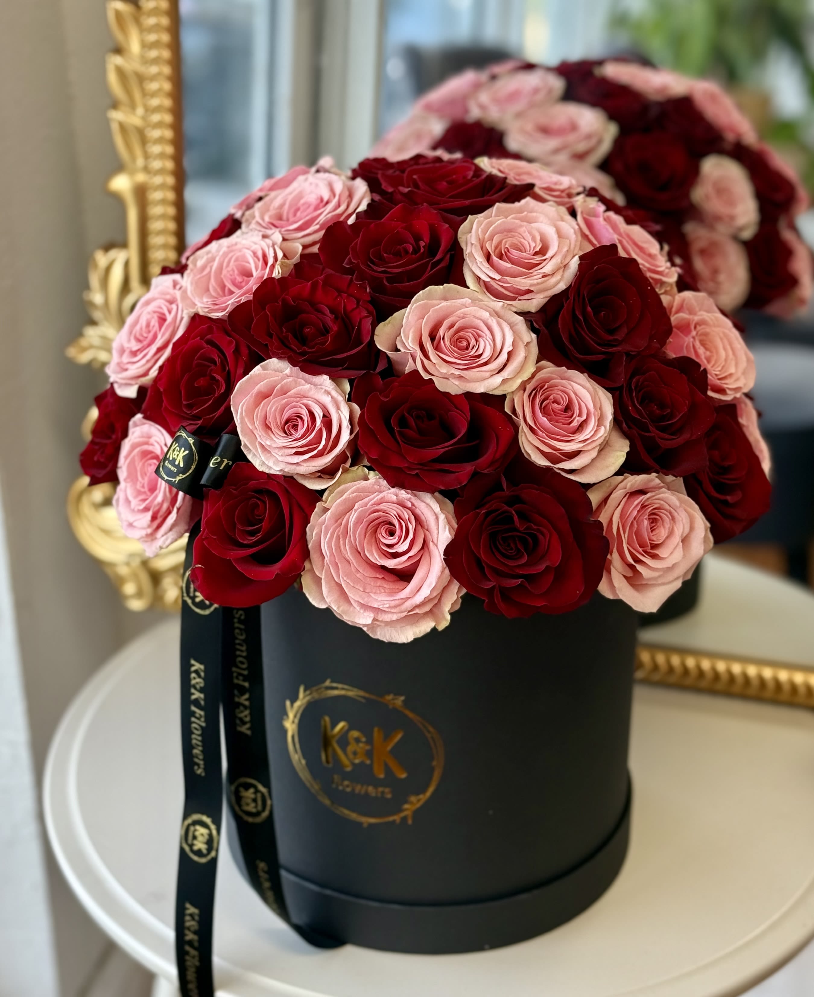 Pink and red roses arranged in a black hat box