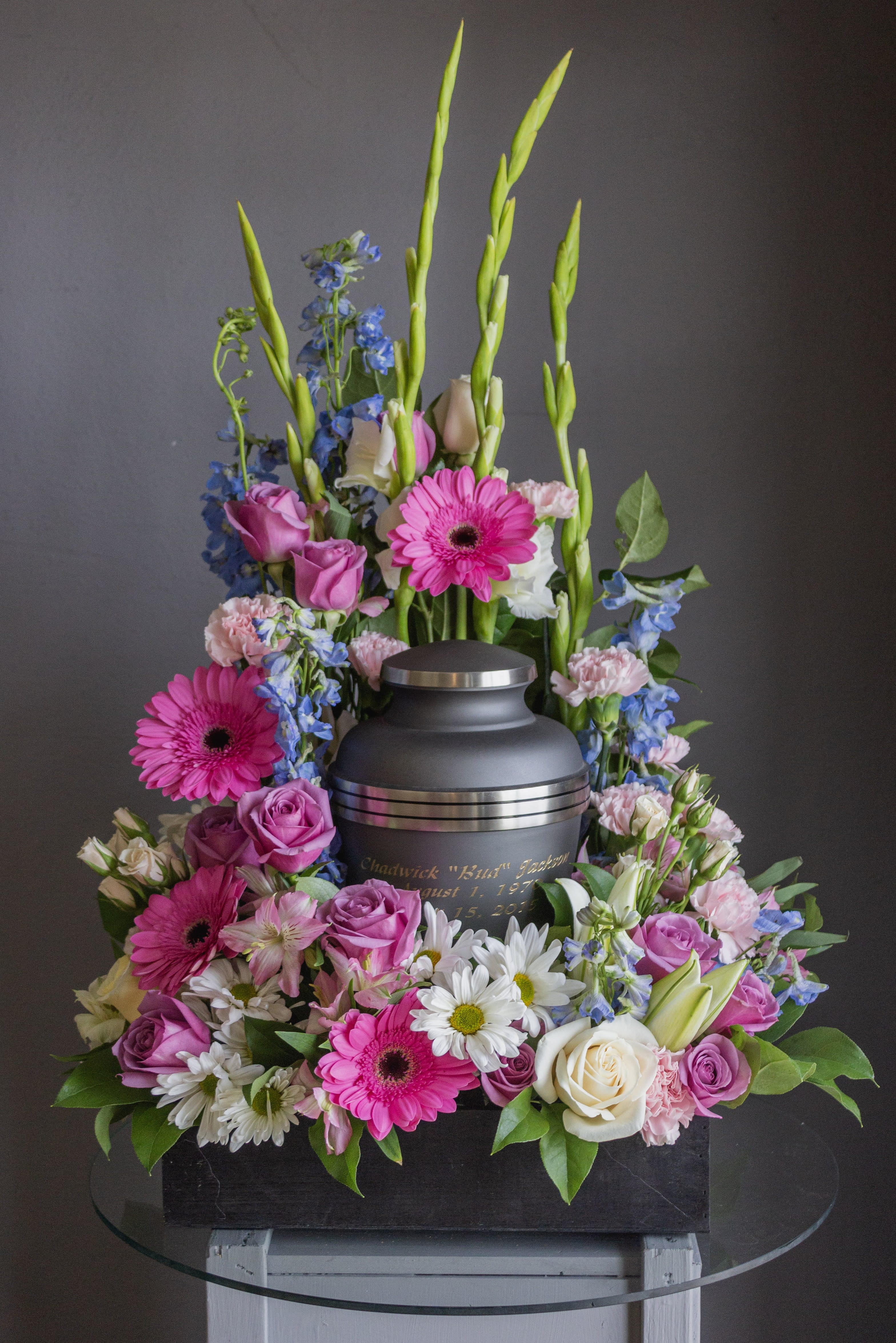 Funeral urn surrounded by pink, white, and blue flowers