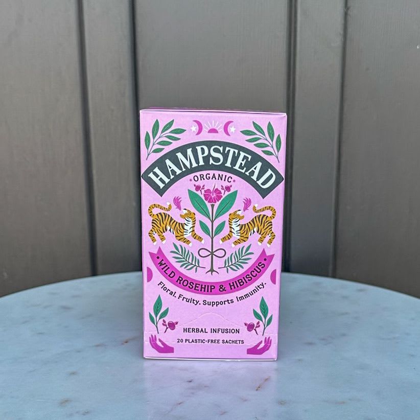 Pink box of Hampstead organic wild rosehip and hibiscus herbal tea on a round table.