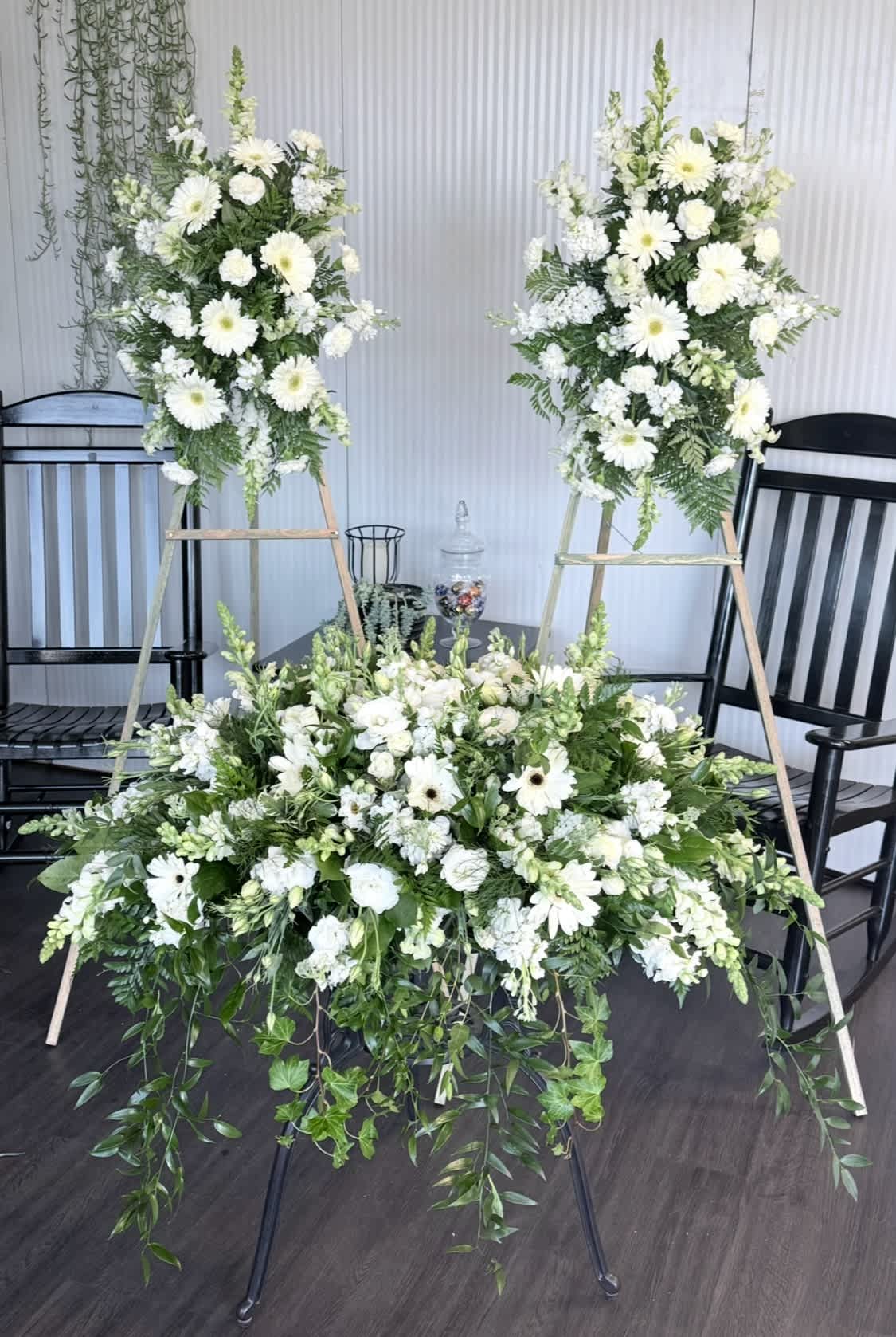 White floral funeral display with two standing sprays and a low arrangement